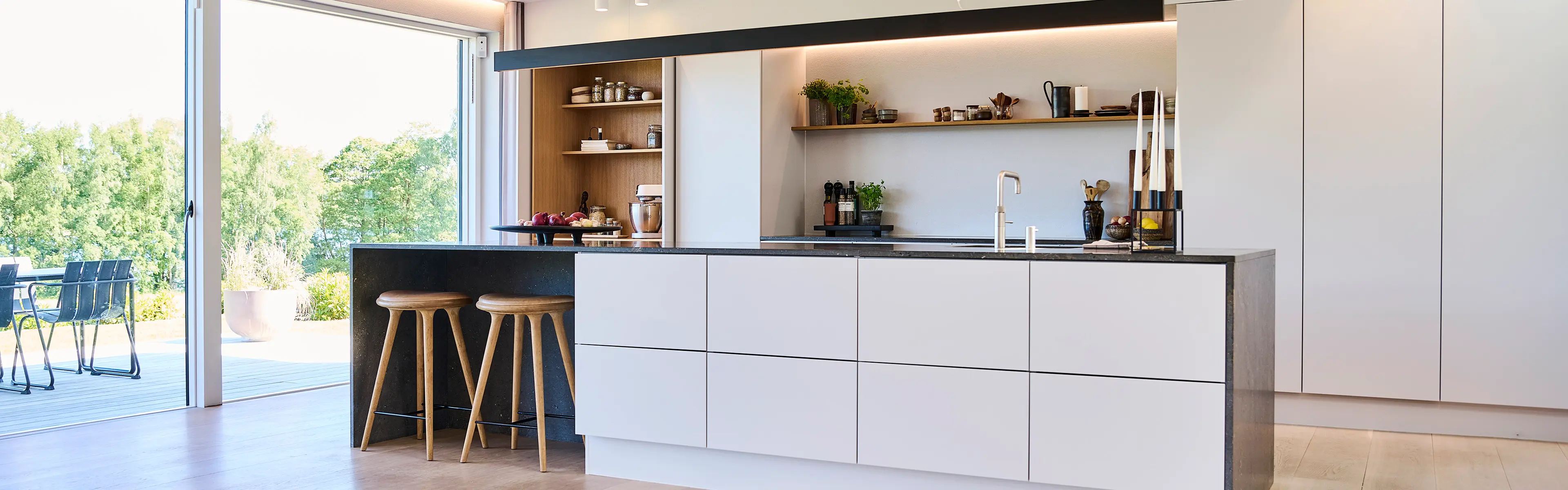 Åpen kjøkkenløsning med kjøkkenøy og utgang til terrasse.