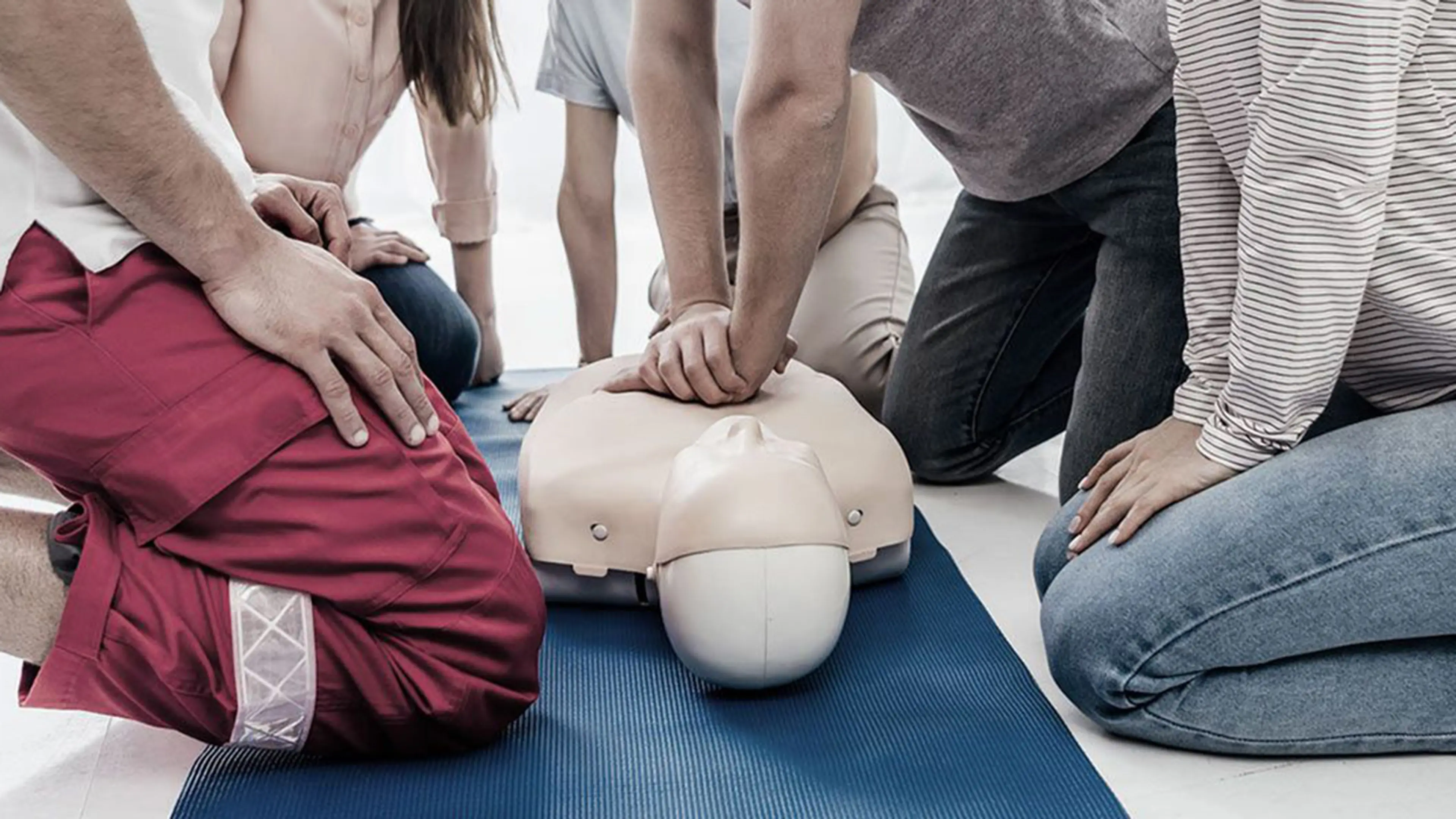 Personer som utfører hjertekompresjoner på dukke på førstehjelpskurs.