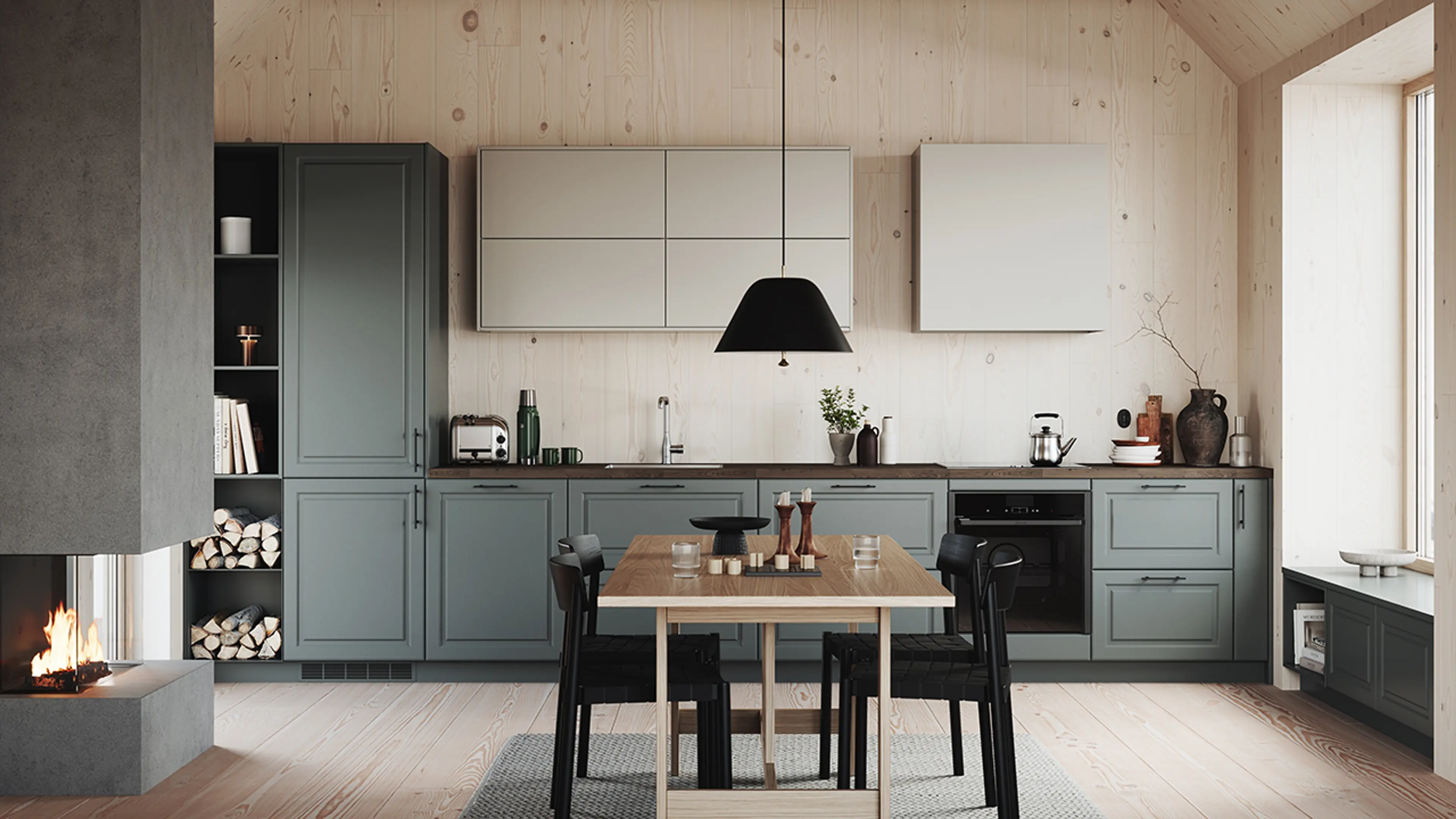 Hyttekjøkken i grønngrå og varm gråfarge med furuvegger og peis ved spiseplassen.