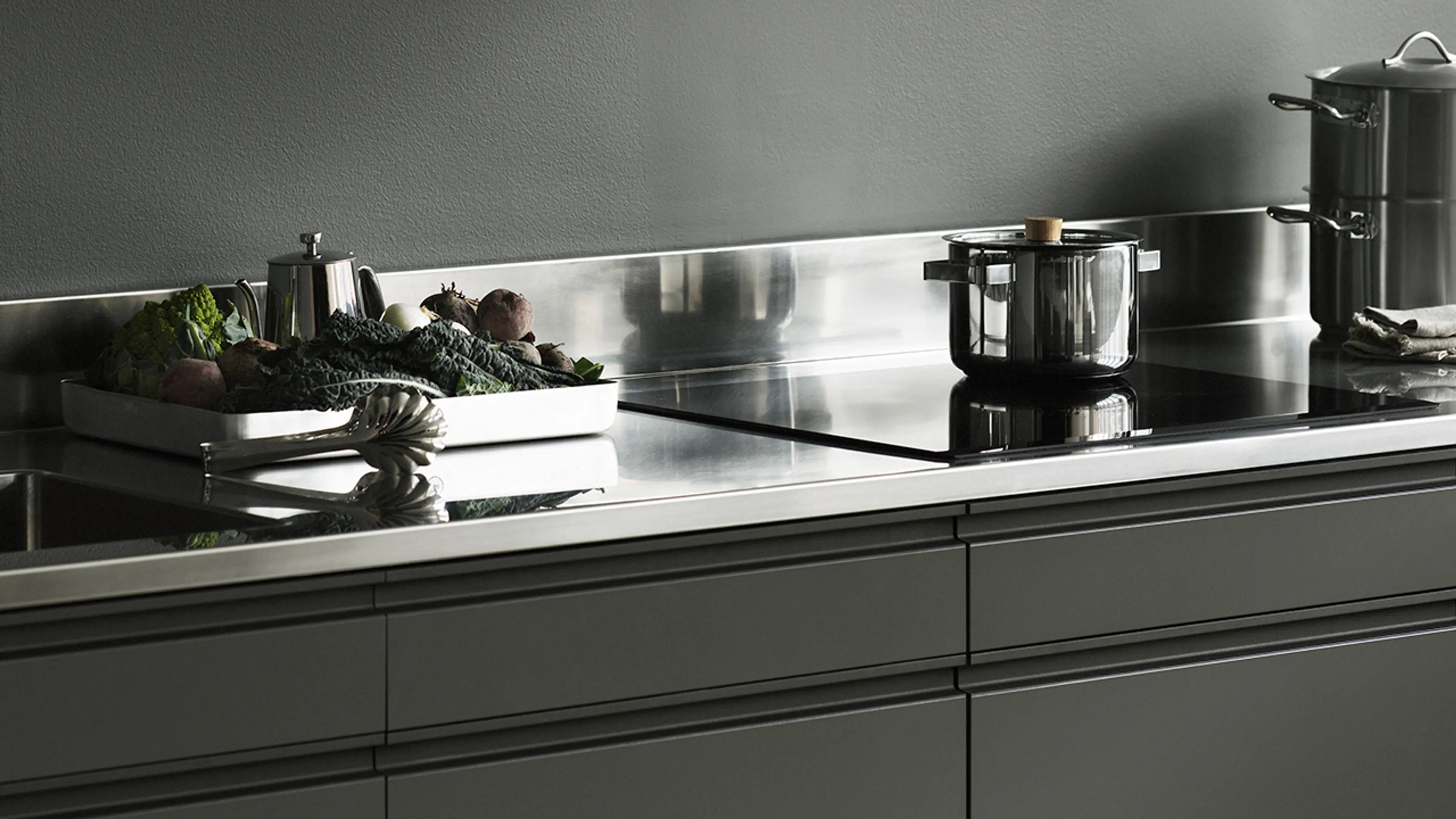 Nærbilde av grønt kjøkken med benkeplate i stål