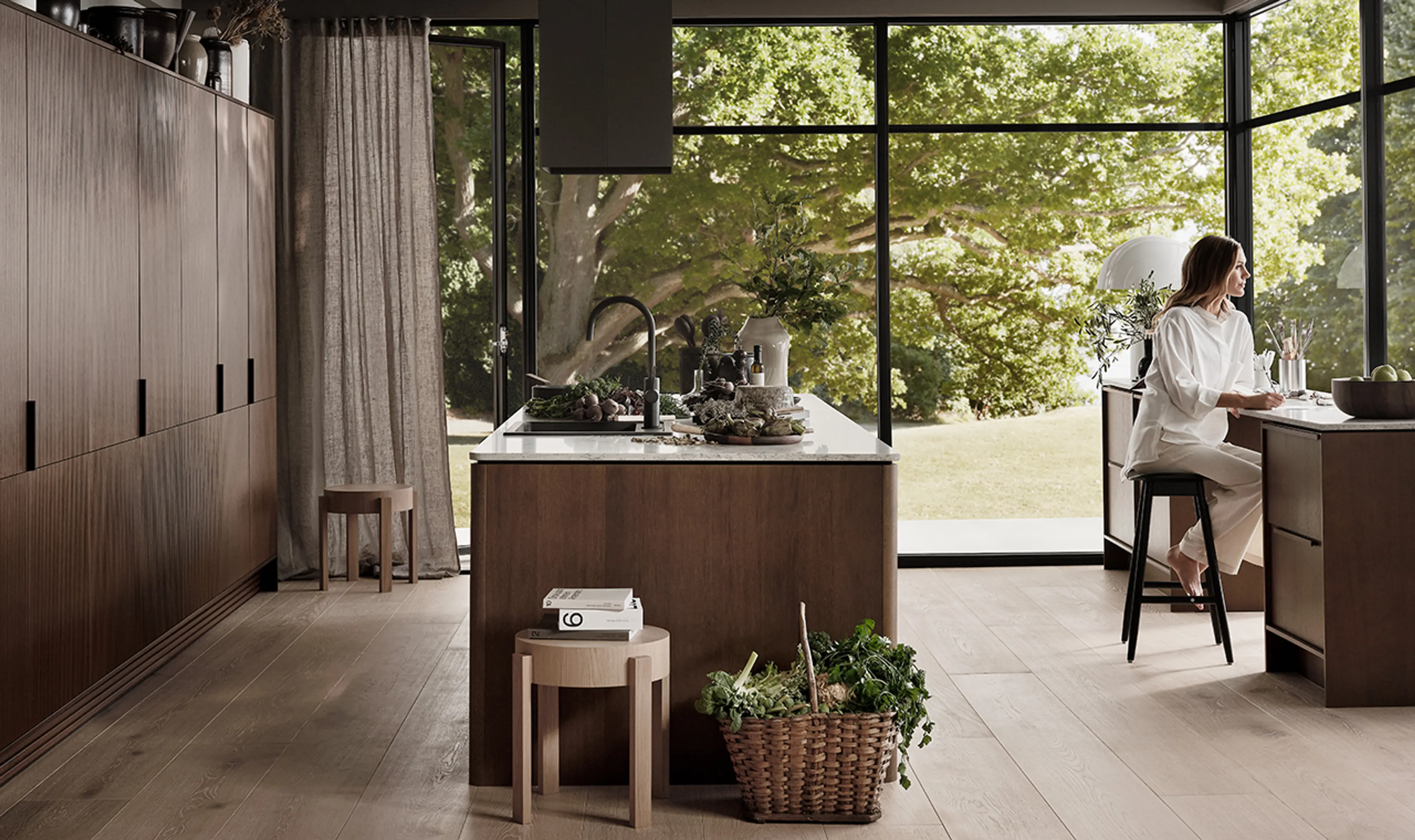 Kvinne som sitter ved skrivebord i rom med åpen kjøkkenløsning.