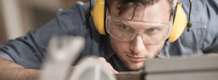 Mann med gule hørselvern og vernebriller