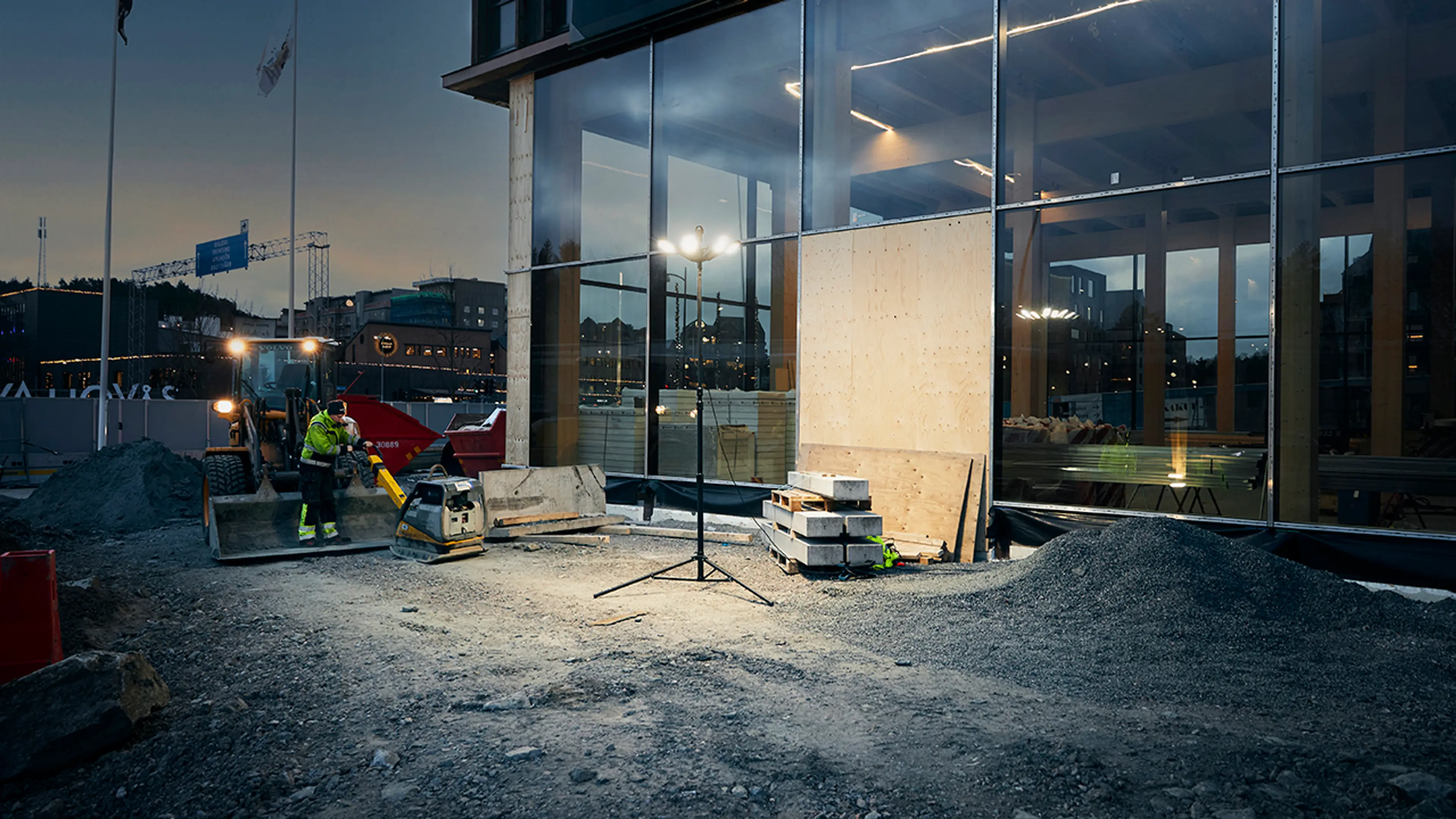 Arbeidslampe med kraftig lys foran glassbygning