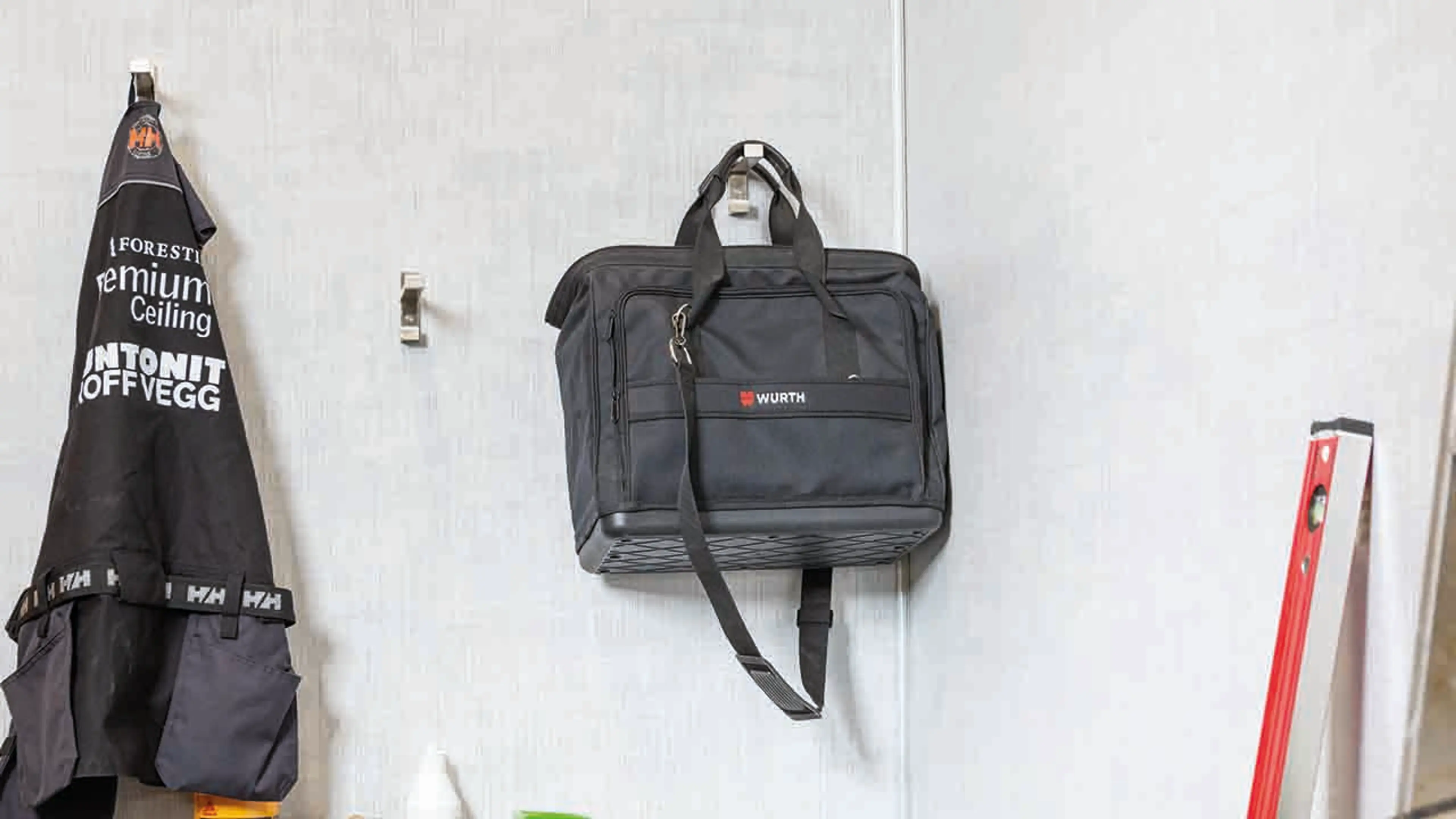 Lyse vegger i driftsbygg på gård med knagger til jakker.