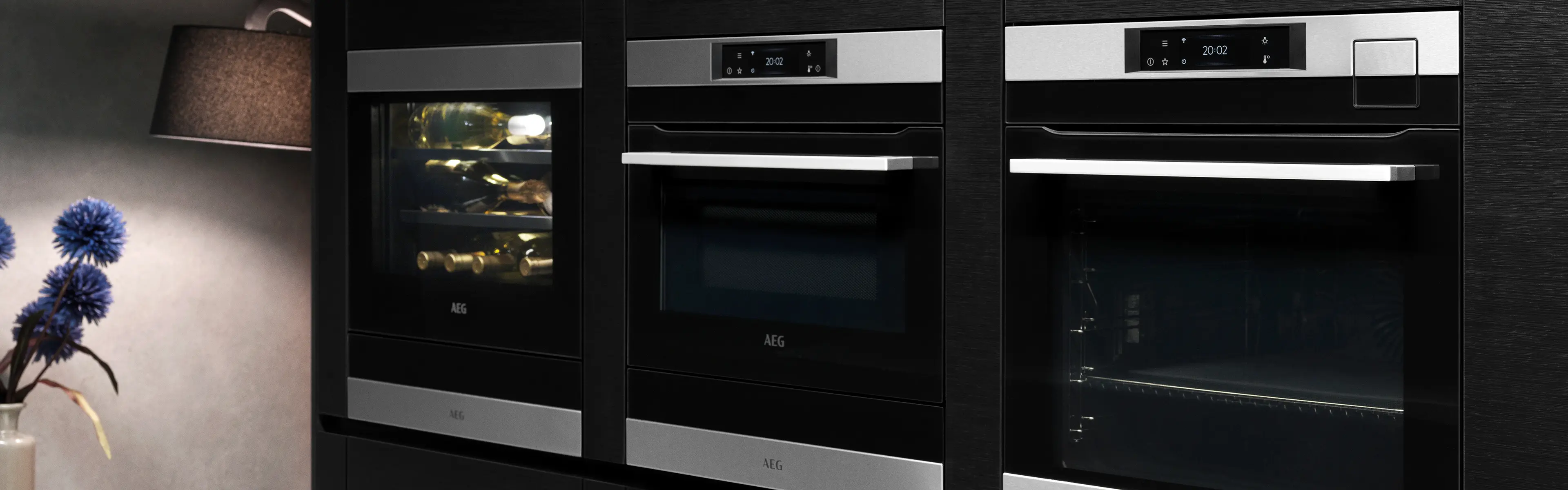 Nærbilde av dampovn og kombiovn i et svart kjøkken.