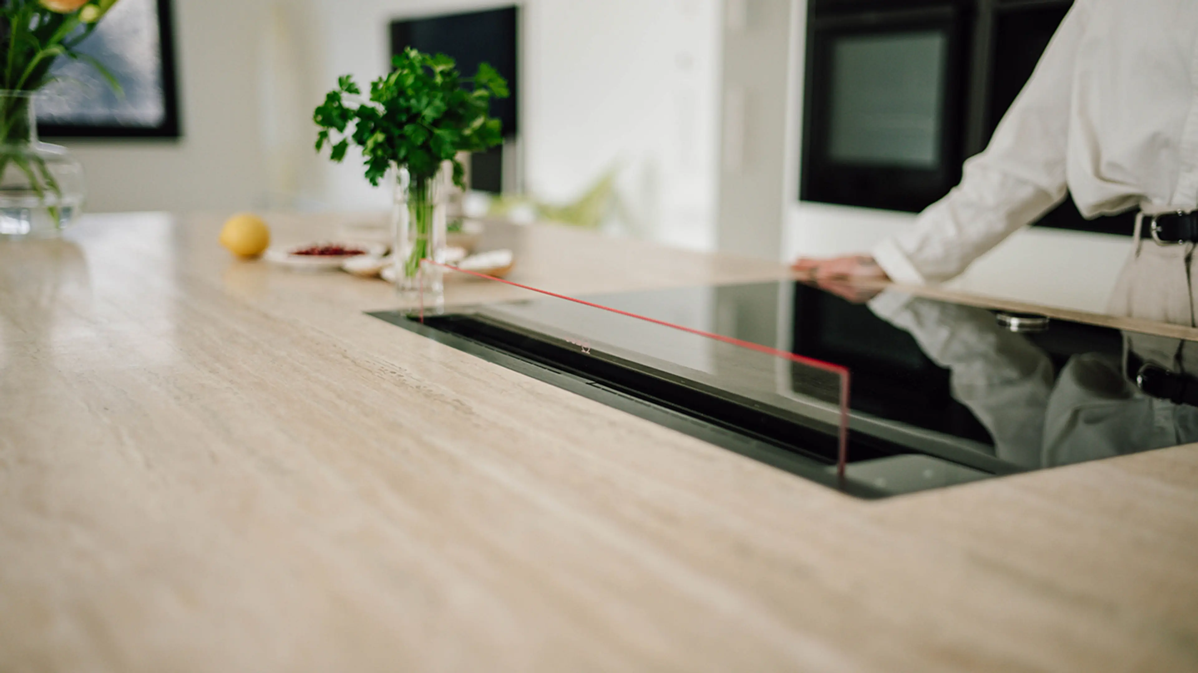 Kjøkkenøy med benkemontert kjøkkenvifte i glass.