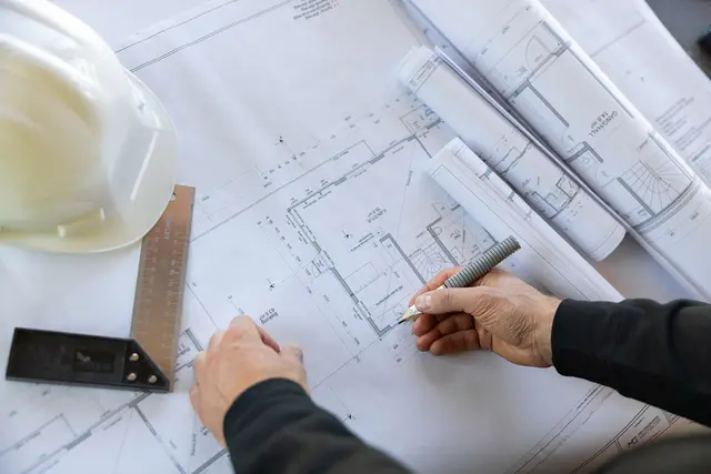 en mann ser på byggetegninger som ligger på et bord