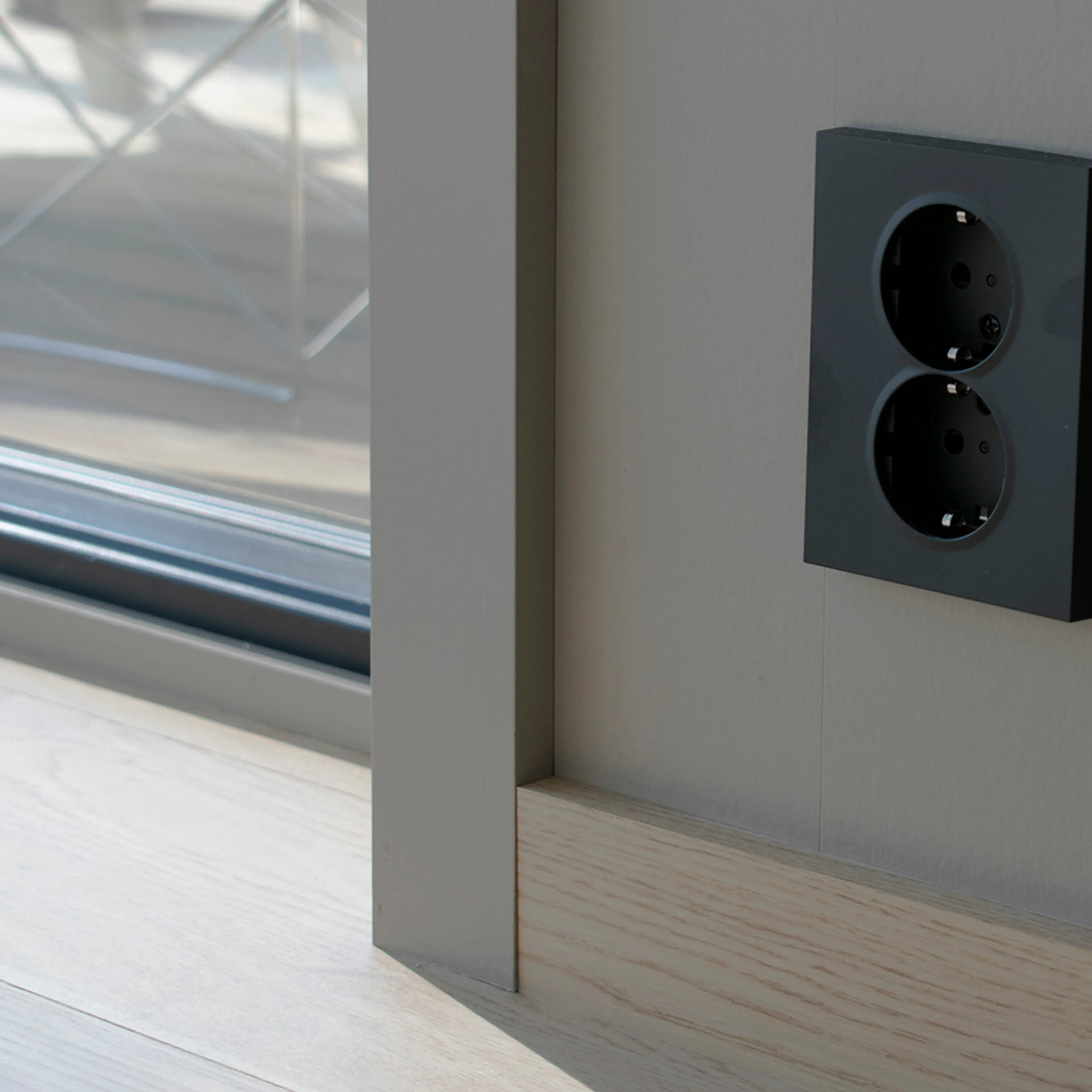 listverk i grå farge og en sort stikkontakt på veggen.