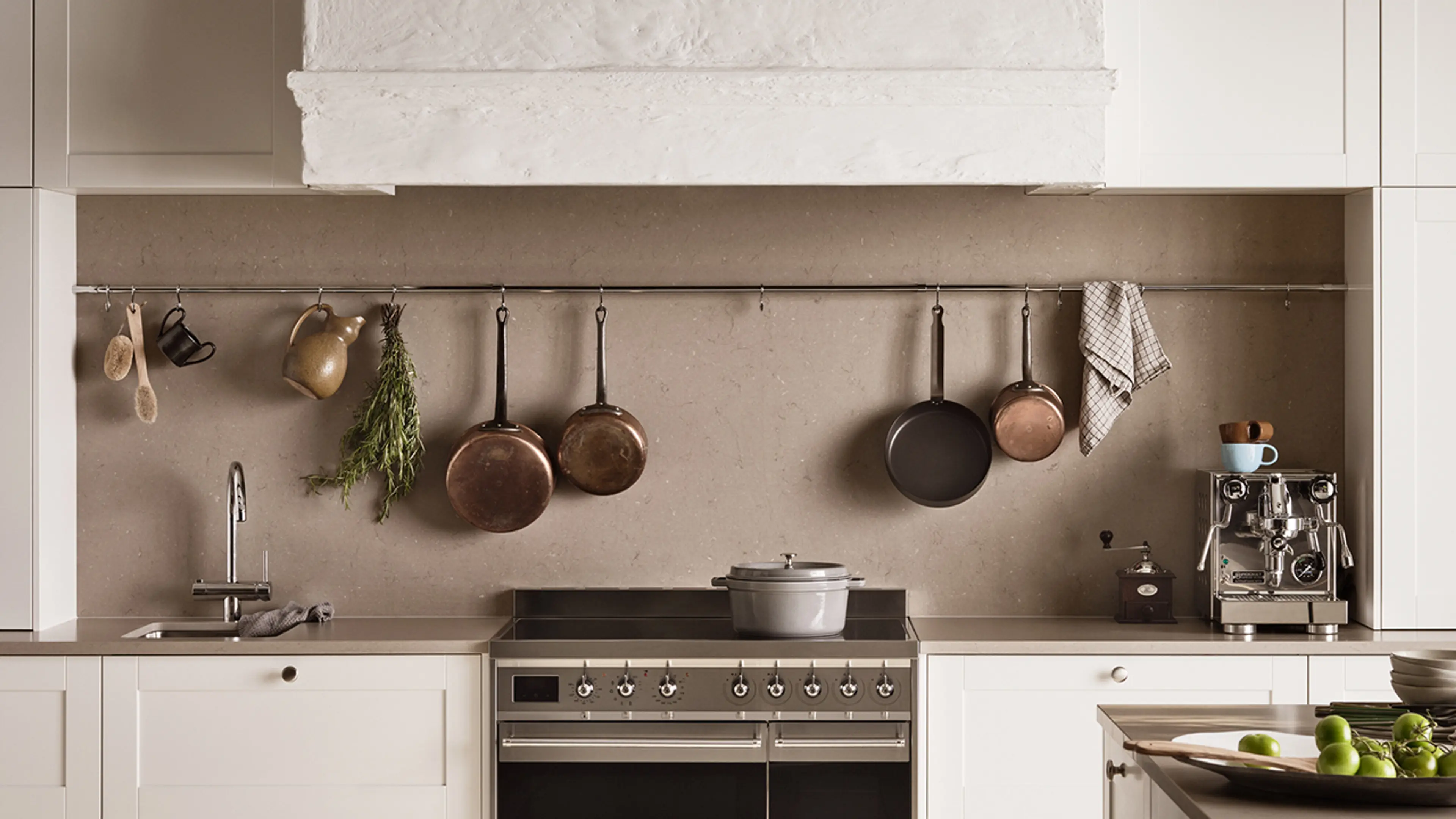 Lyst landlig hyttekjøkken med stekeovn, kaffemaskin, servant og blandebatteri i krom.