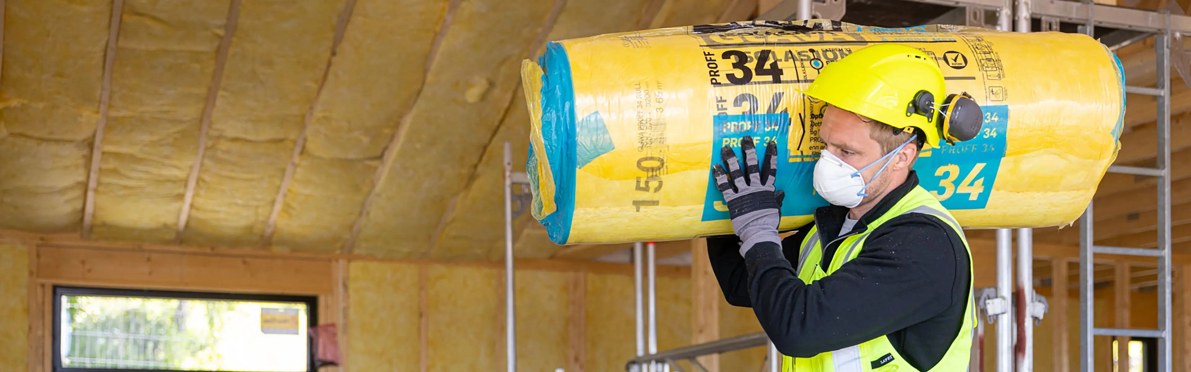 Håndverker bærer en rull med Glava isolasjon inne i et hus