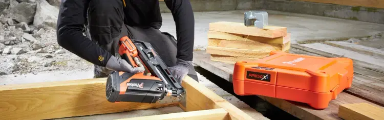 snekker på byggeplass som jobber med dykkertpistol fra Paslode