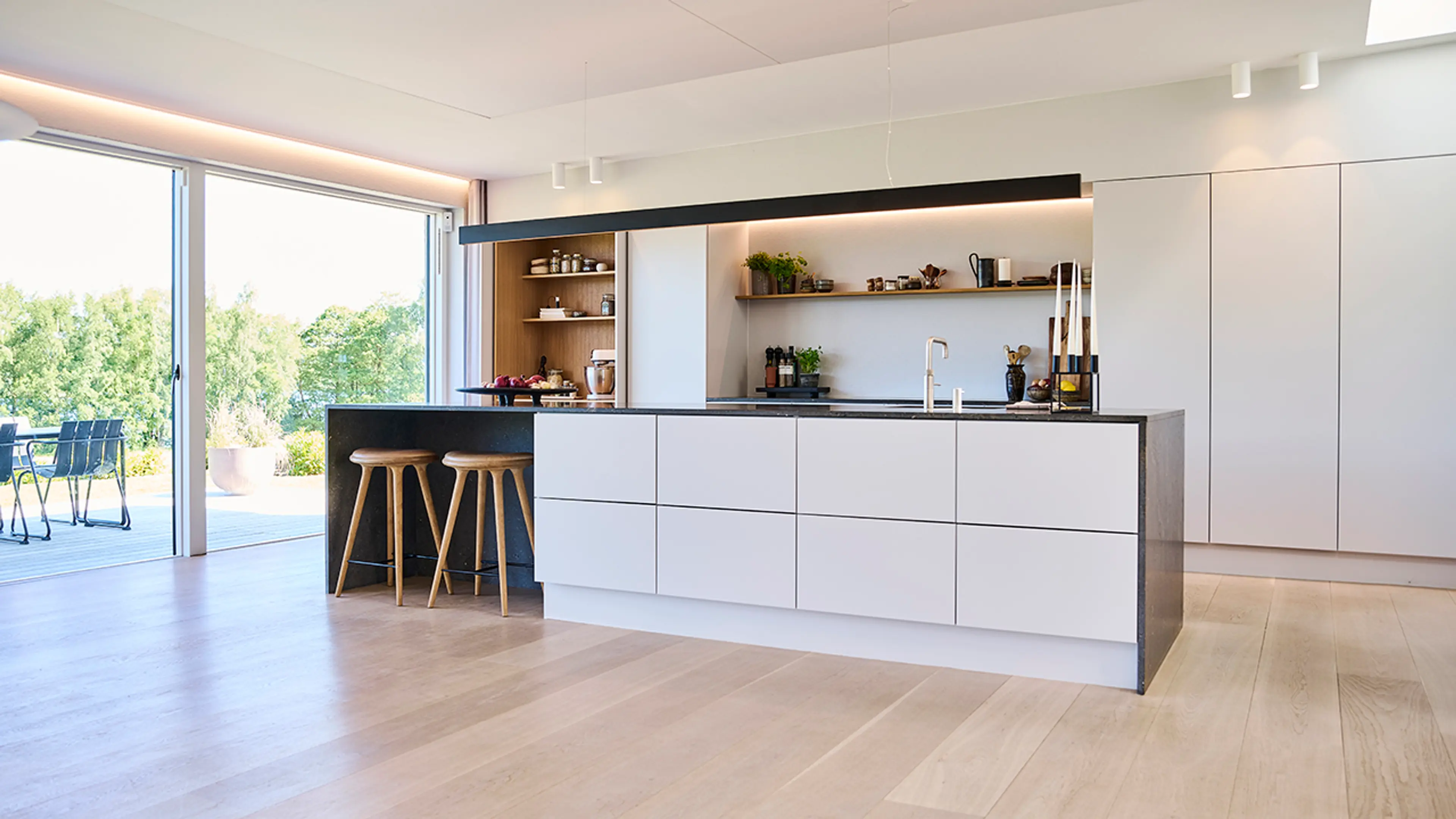 Åpen kjøkkenløsning med kjøkkenøy og utgang til terrasse.