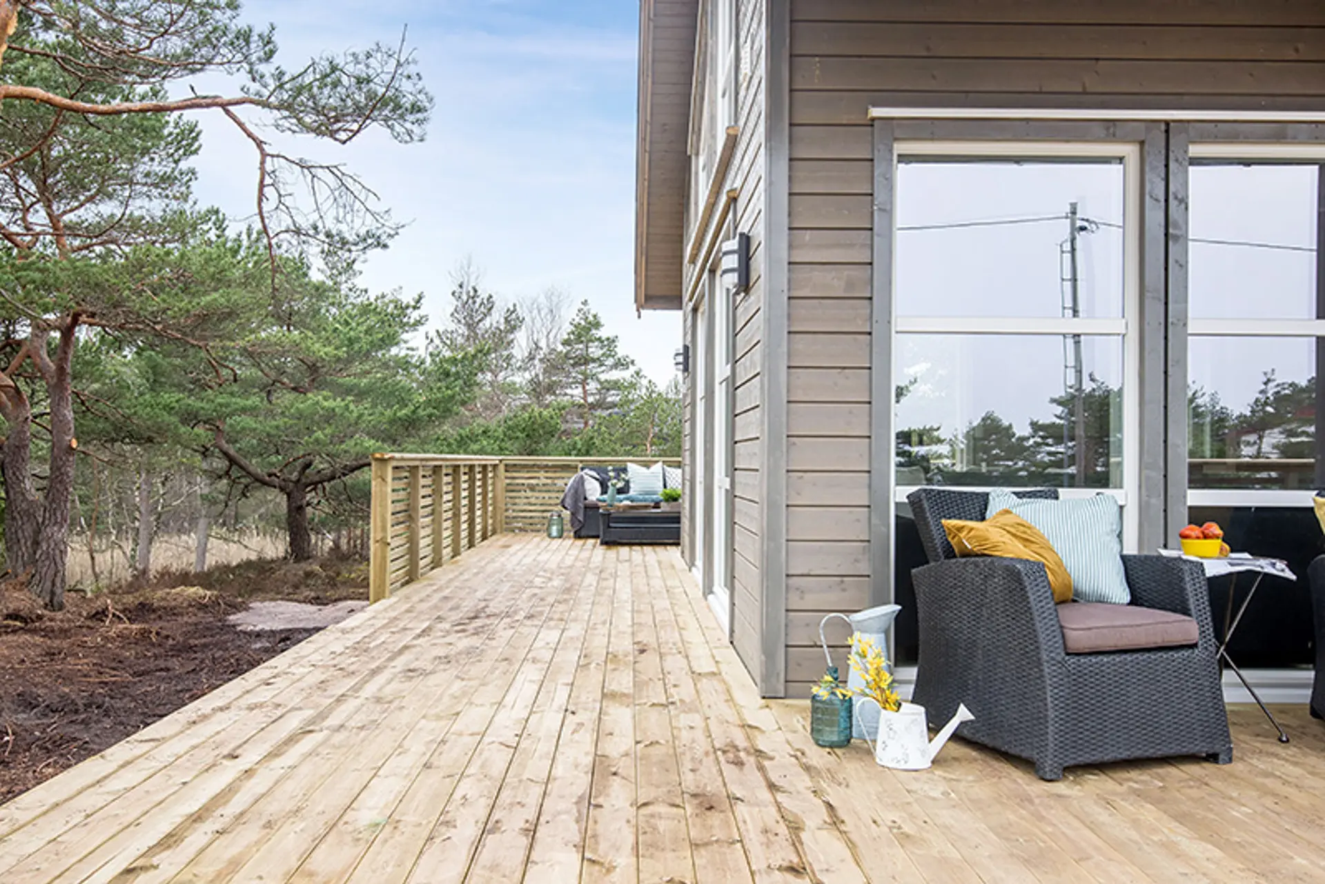 Nybygget terrasse på hytte. Rottingmøbler står foran vinduet