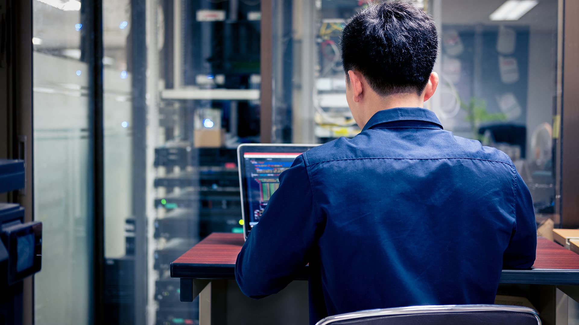 Employee working on a computer in a server room.