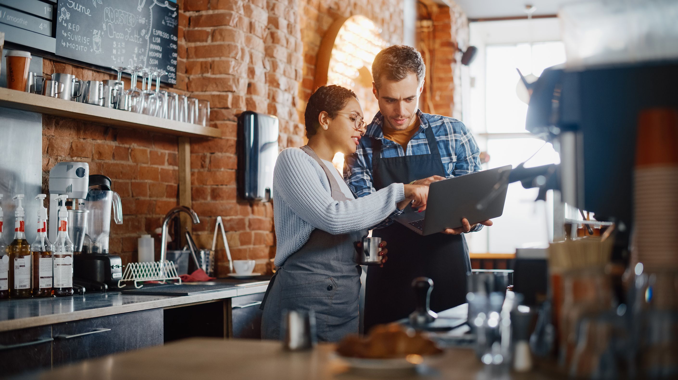 People using wireless internet to discuss work on a laptop within a cafe.