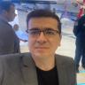 photo of the owner wearing glasses and a suit is standing