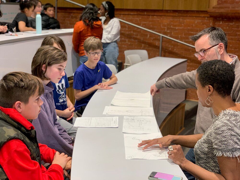 Image of students and teachers working together on a project at a table.