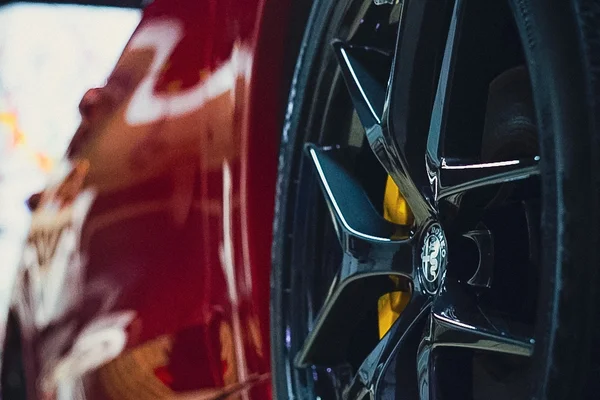 Close-up of a high-gloss red sports car with a premium ceramic coating and polished black rims at Beyond Detail in Scarborough.