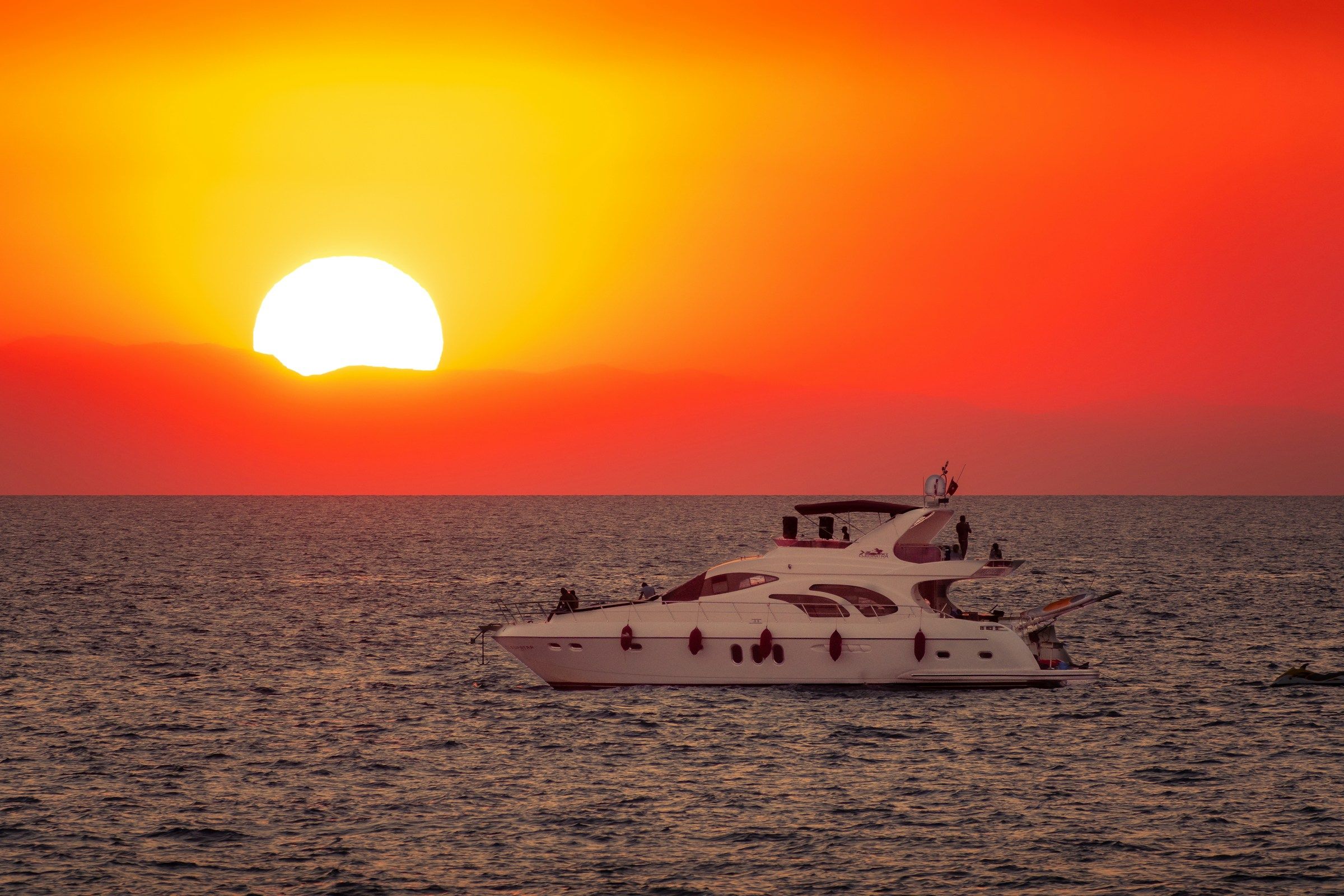 A yacht at sea beneath a red sunset