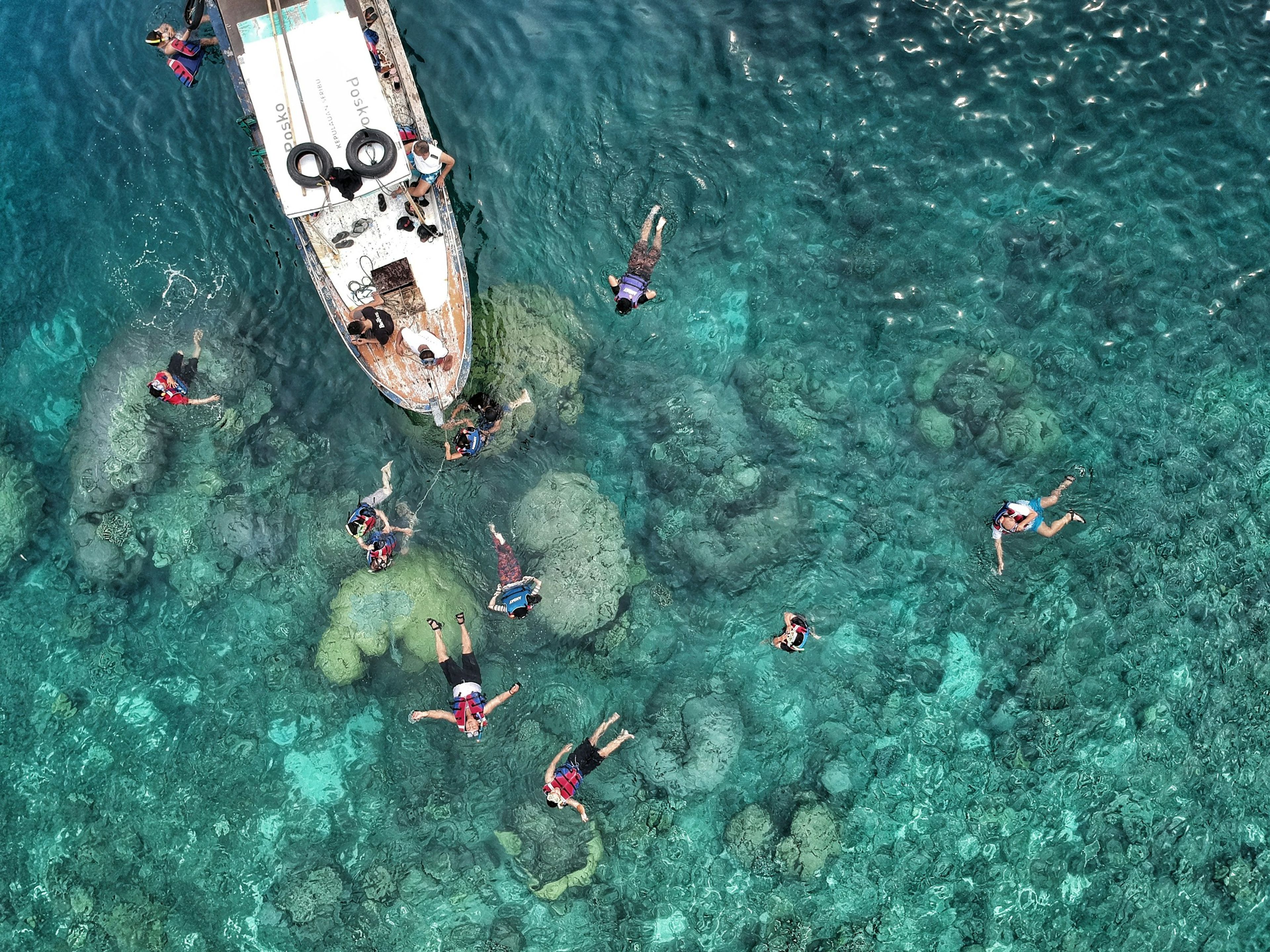 People swimming beside a boat