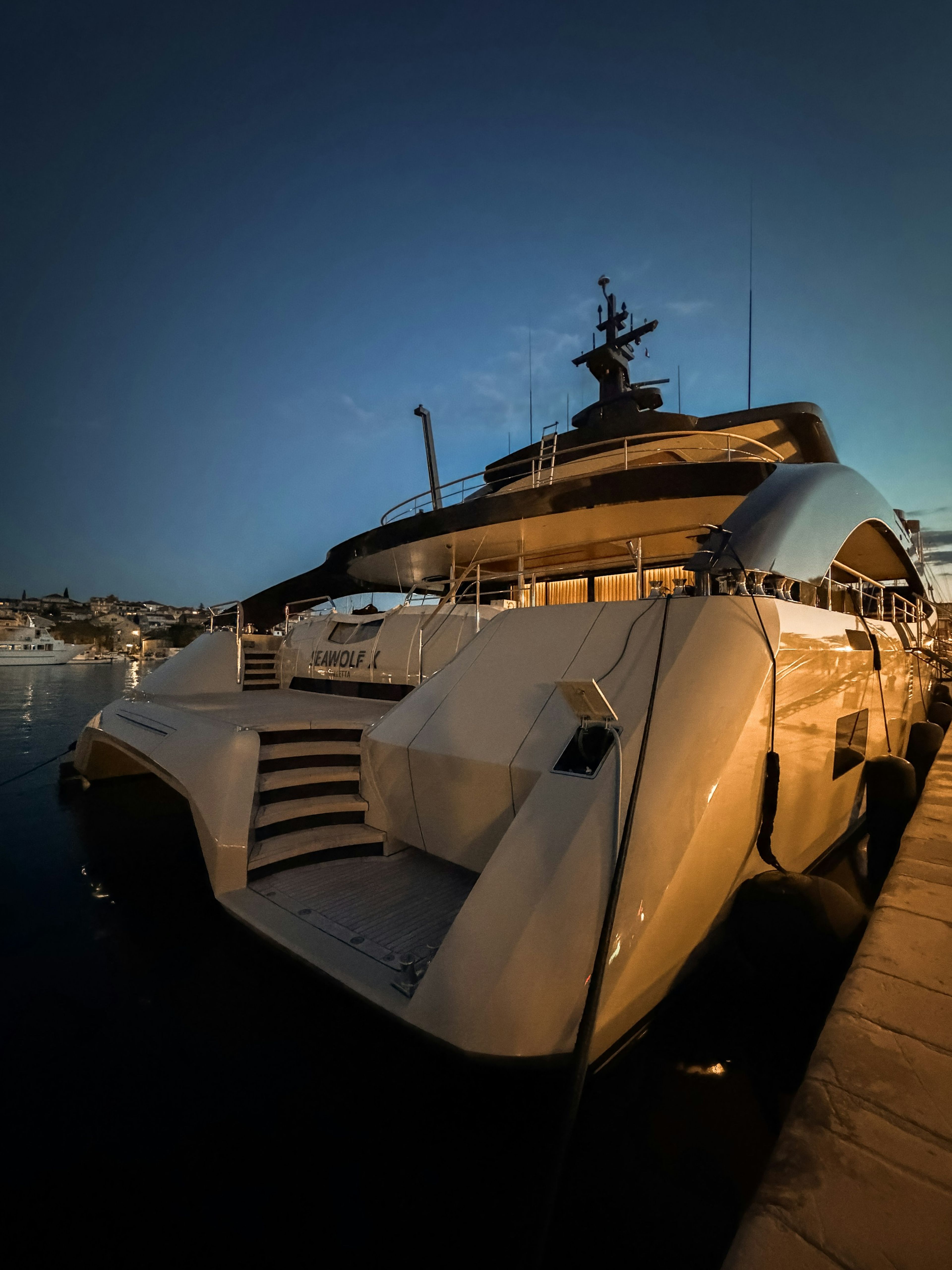 A superyacht docked in a harbour at night