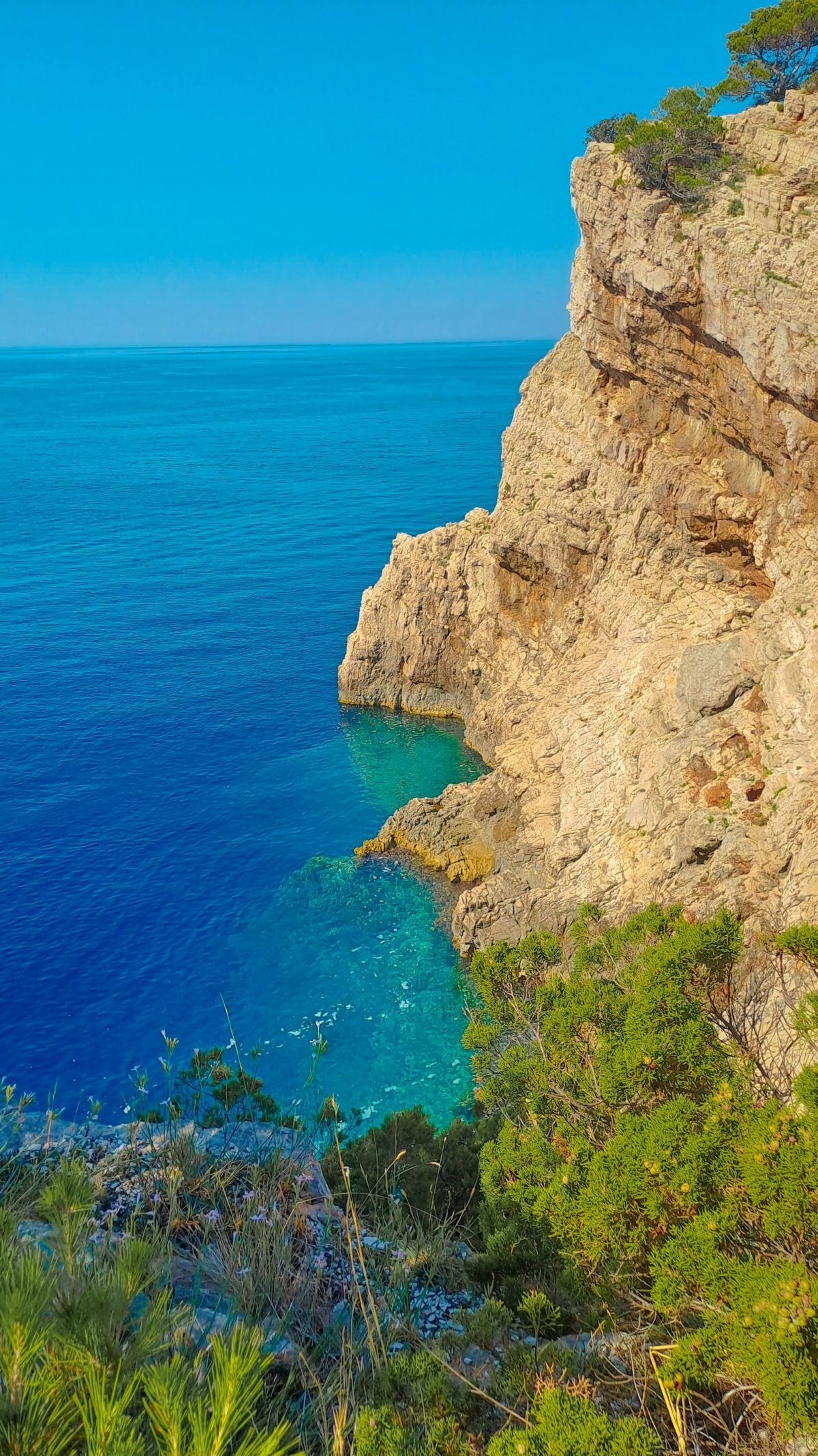A cliff above clear blue water