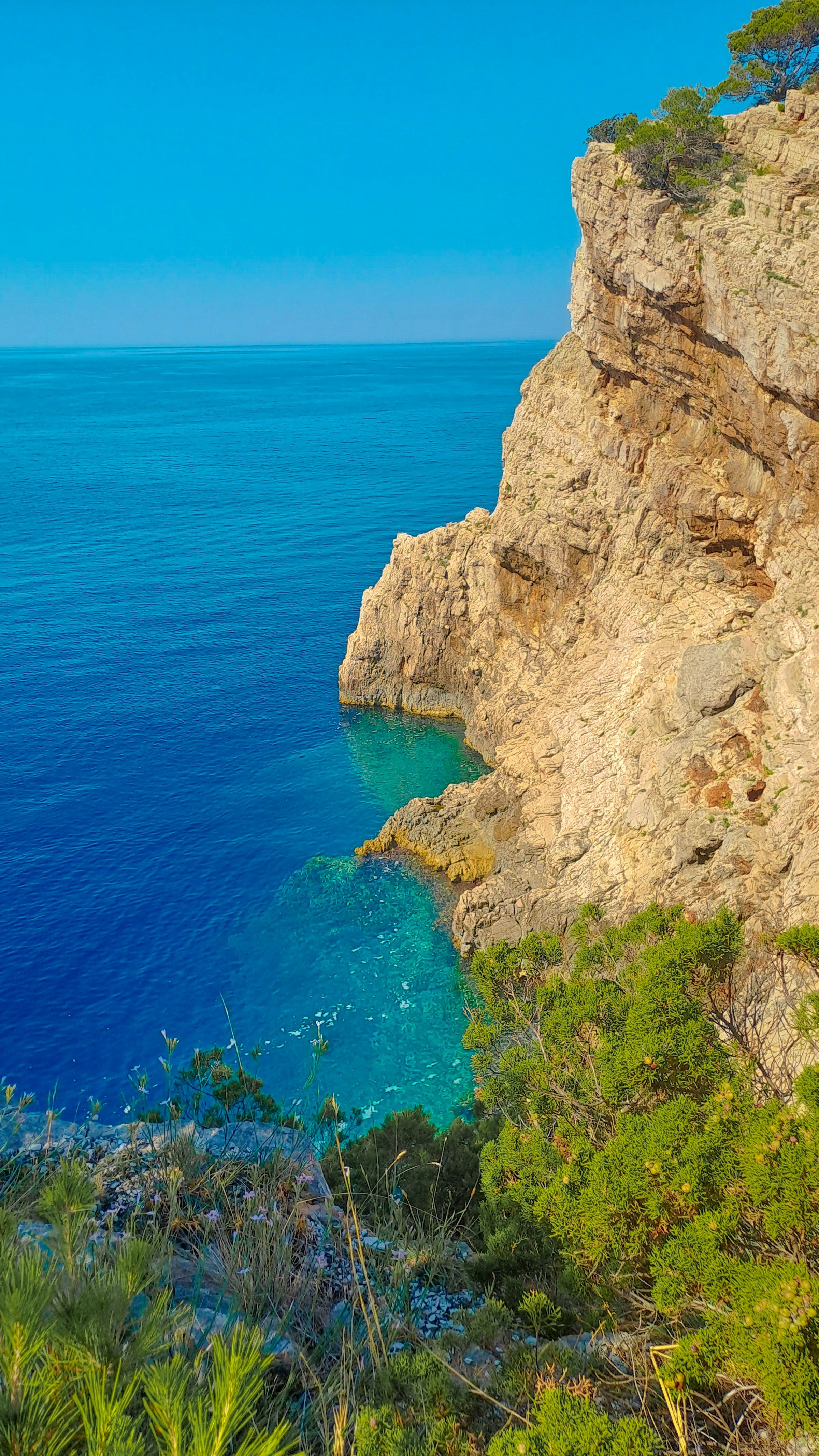 A cliff above clear blue water