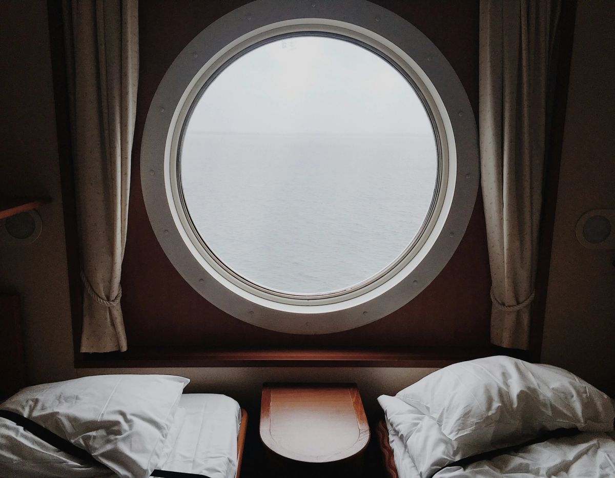 A guest cabin with a round mirror and white linen