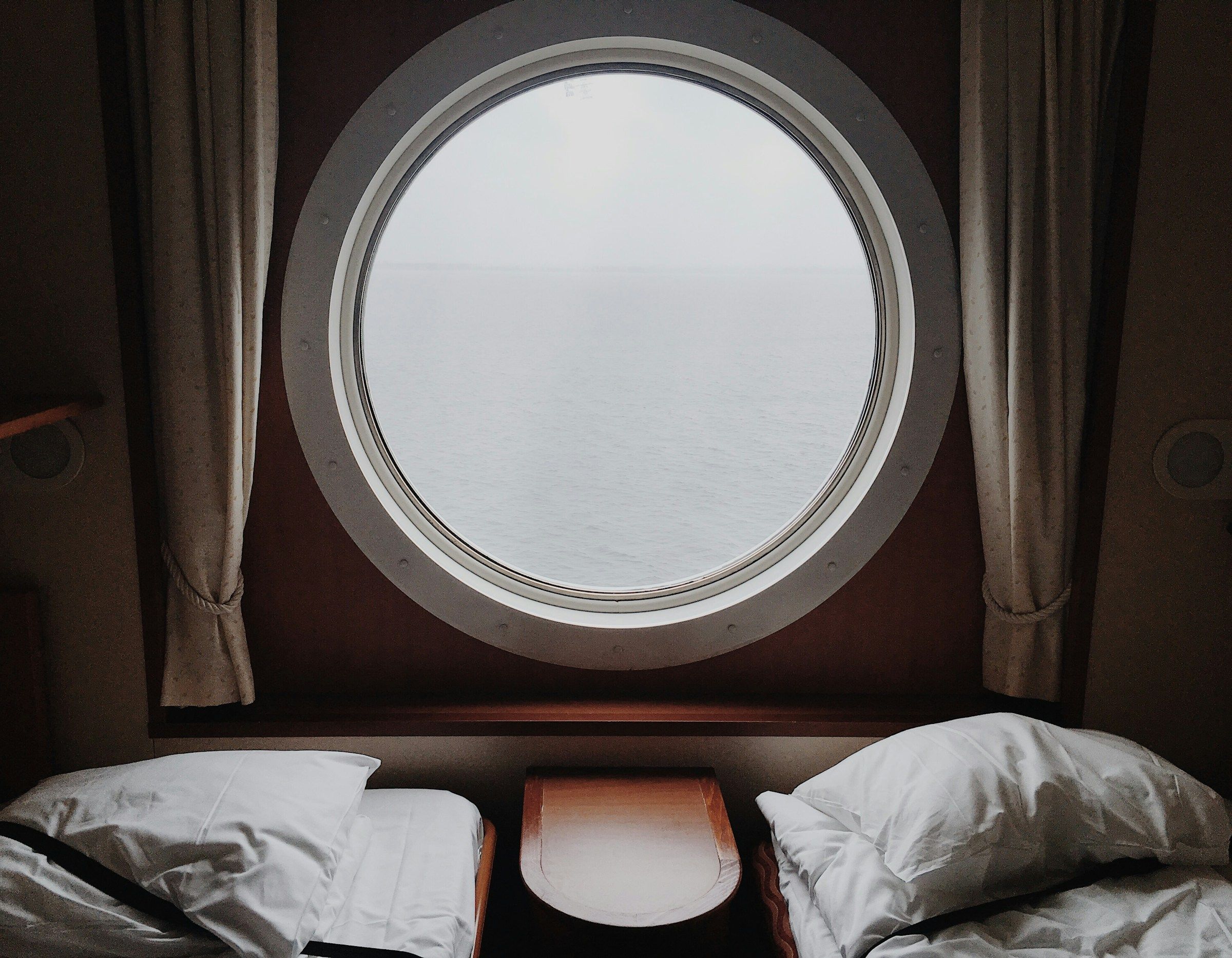 A guest cabin with a round mirror and white linen