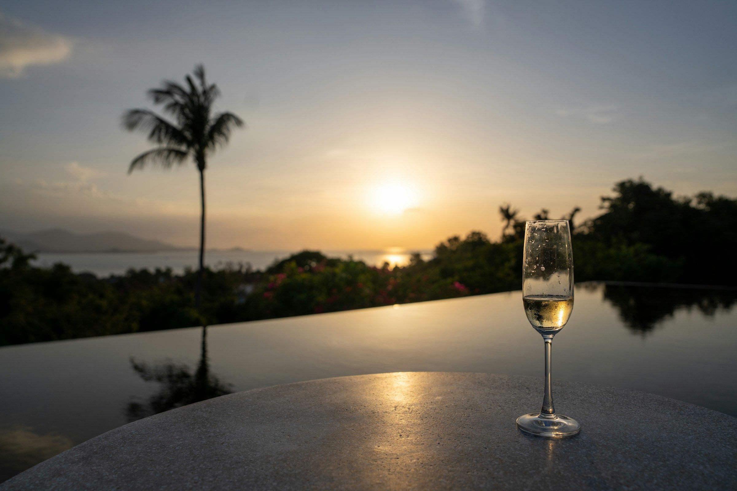 A glass of champagne by an infinity pool at sunset