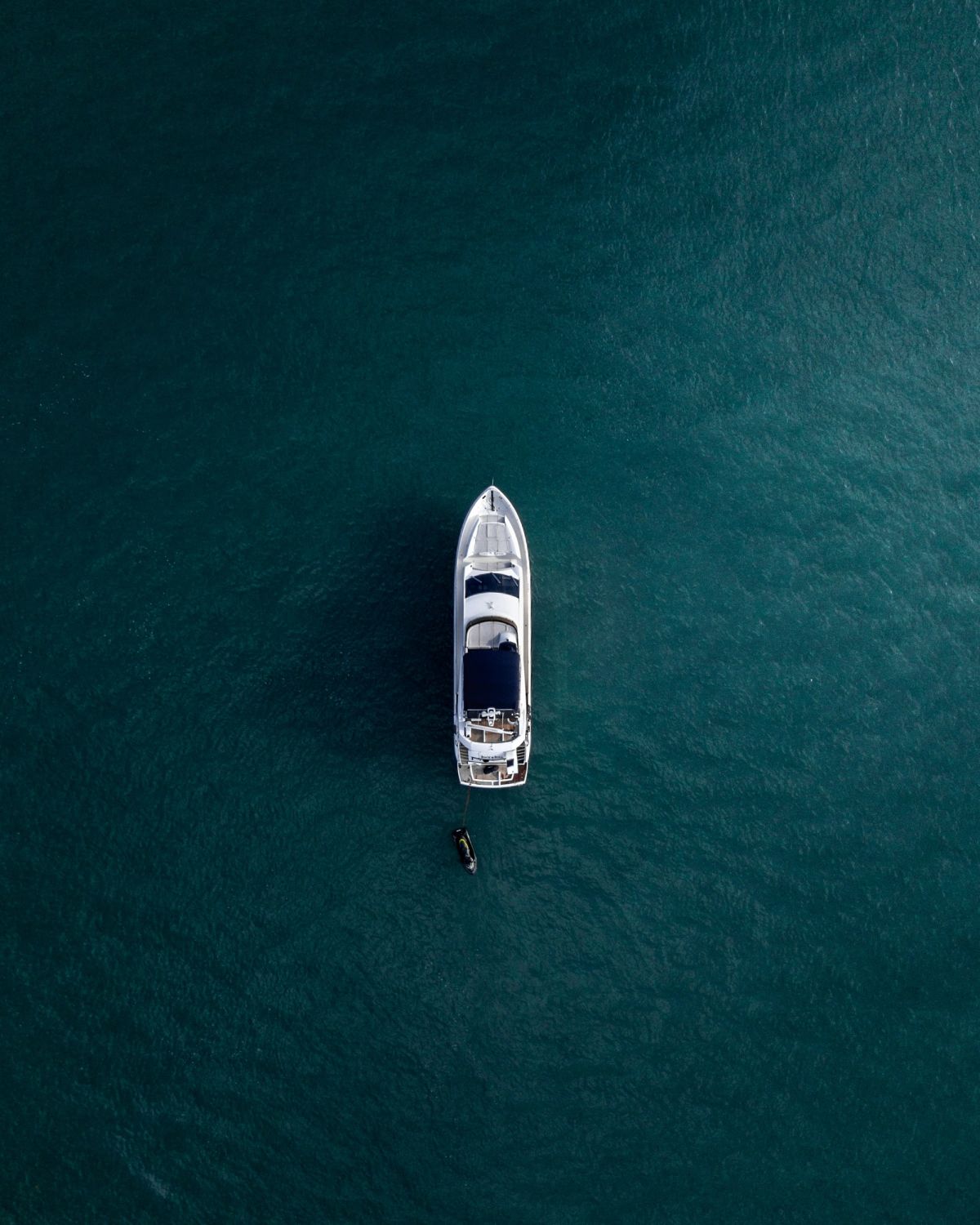 A white yacht alone on deep blue water, seen from above