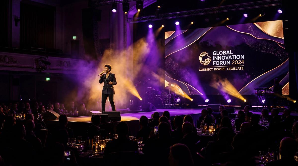 Dark cinematic shot of a performer on a corporate stage with dramatic uplighting, audience silhouettes in foreground