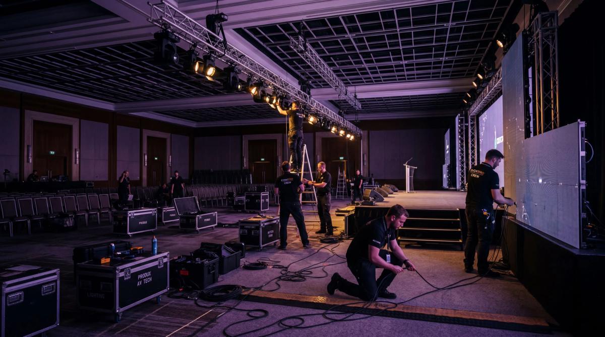 Behind-the-scenes production crew setting up interactive entertainment equipment at a corporate venue