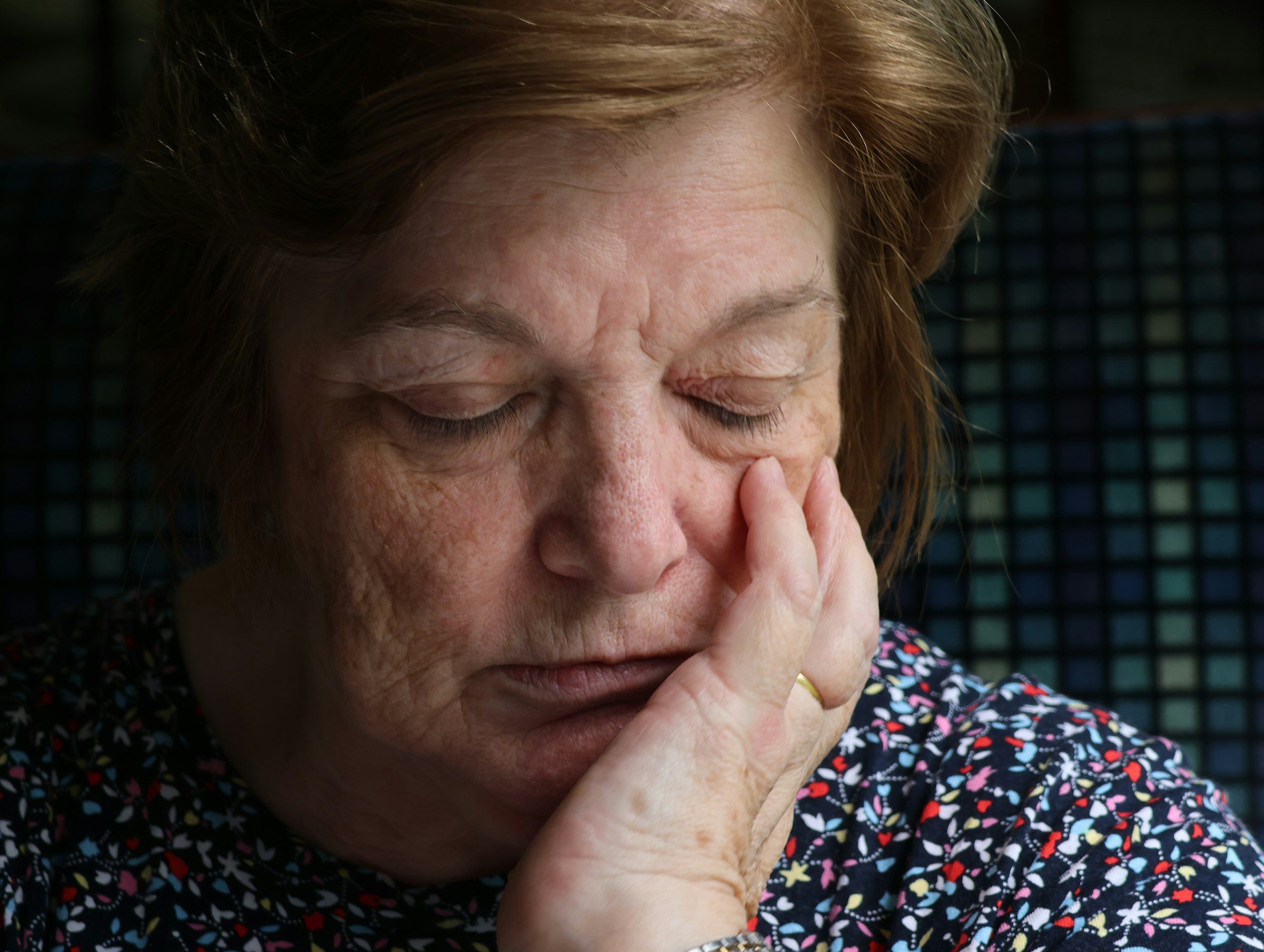 Eldre kvinne som holder hånden mot kinnet som om hun kjenner smerte