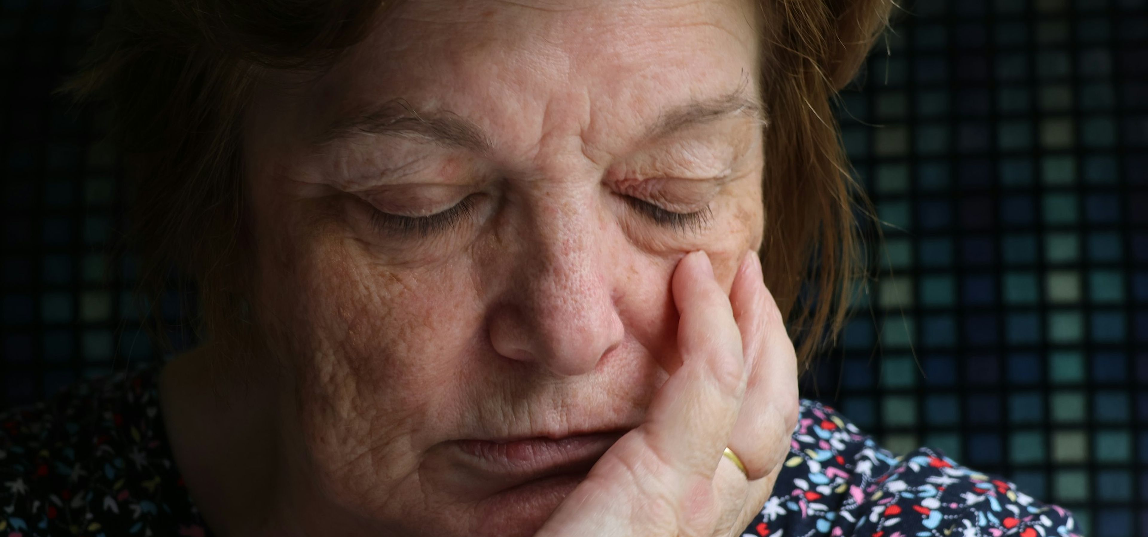 Eldre kvinne som holder hånden mot kinnet som om hun kjenner smerte