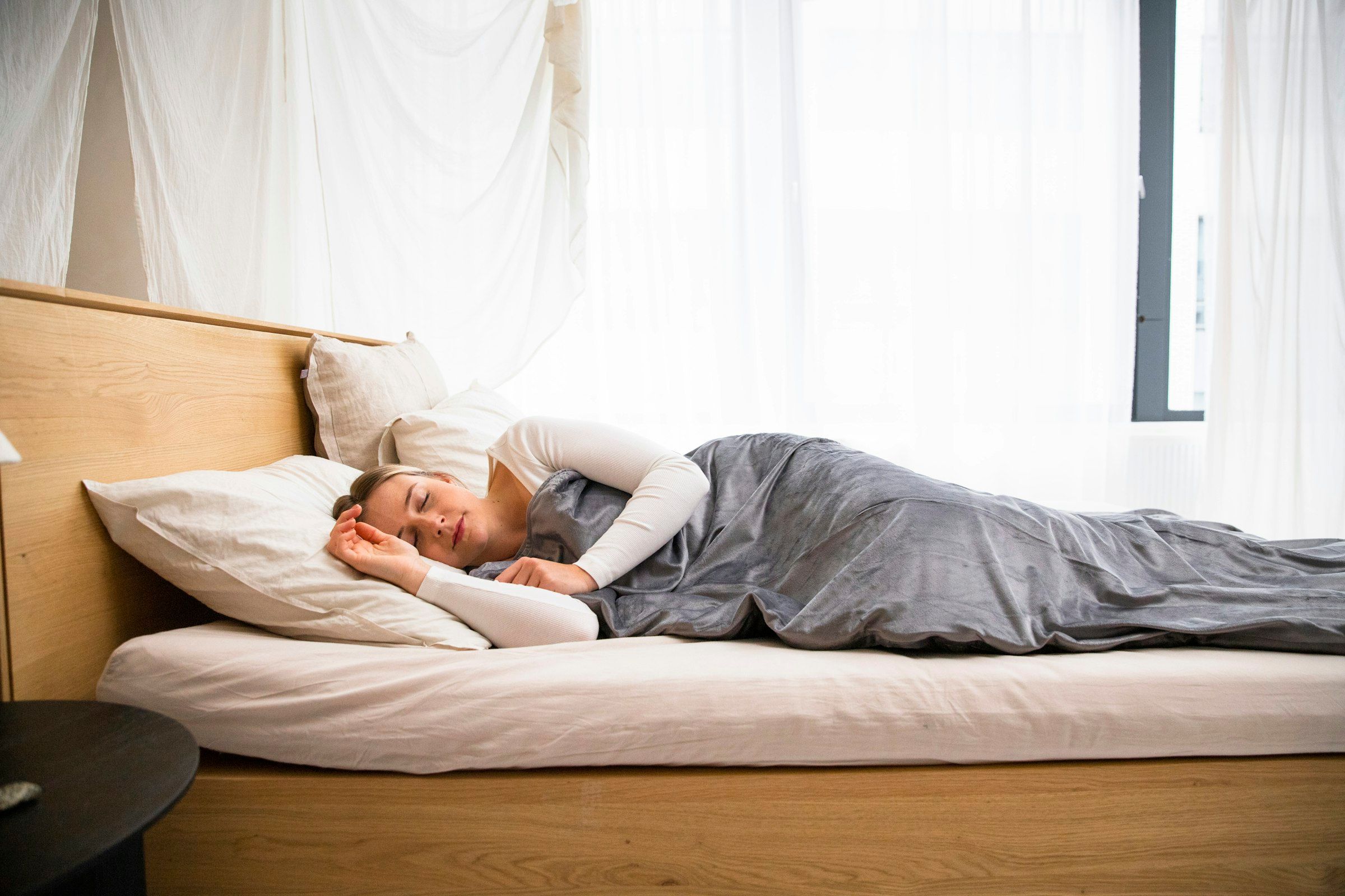 Mann ligger i sengen under et teppe og sover dypt om natten