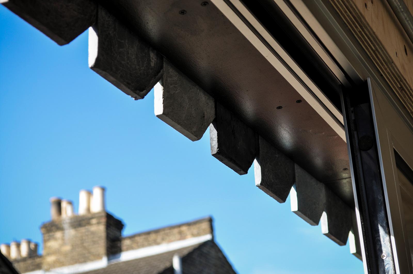 Window detail with overhanging roof tiles at Holloway Lightbox