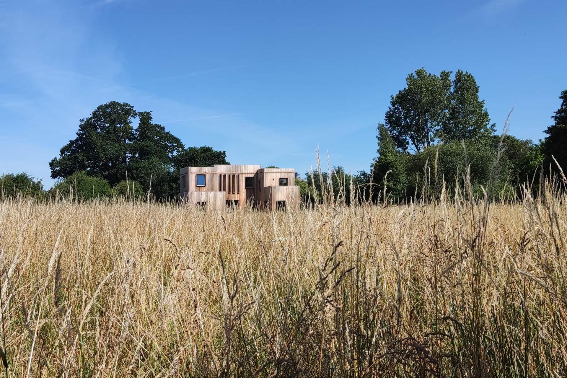 Timber clad house set in meadow field
