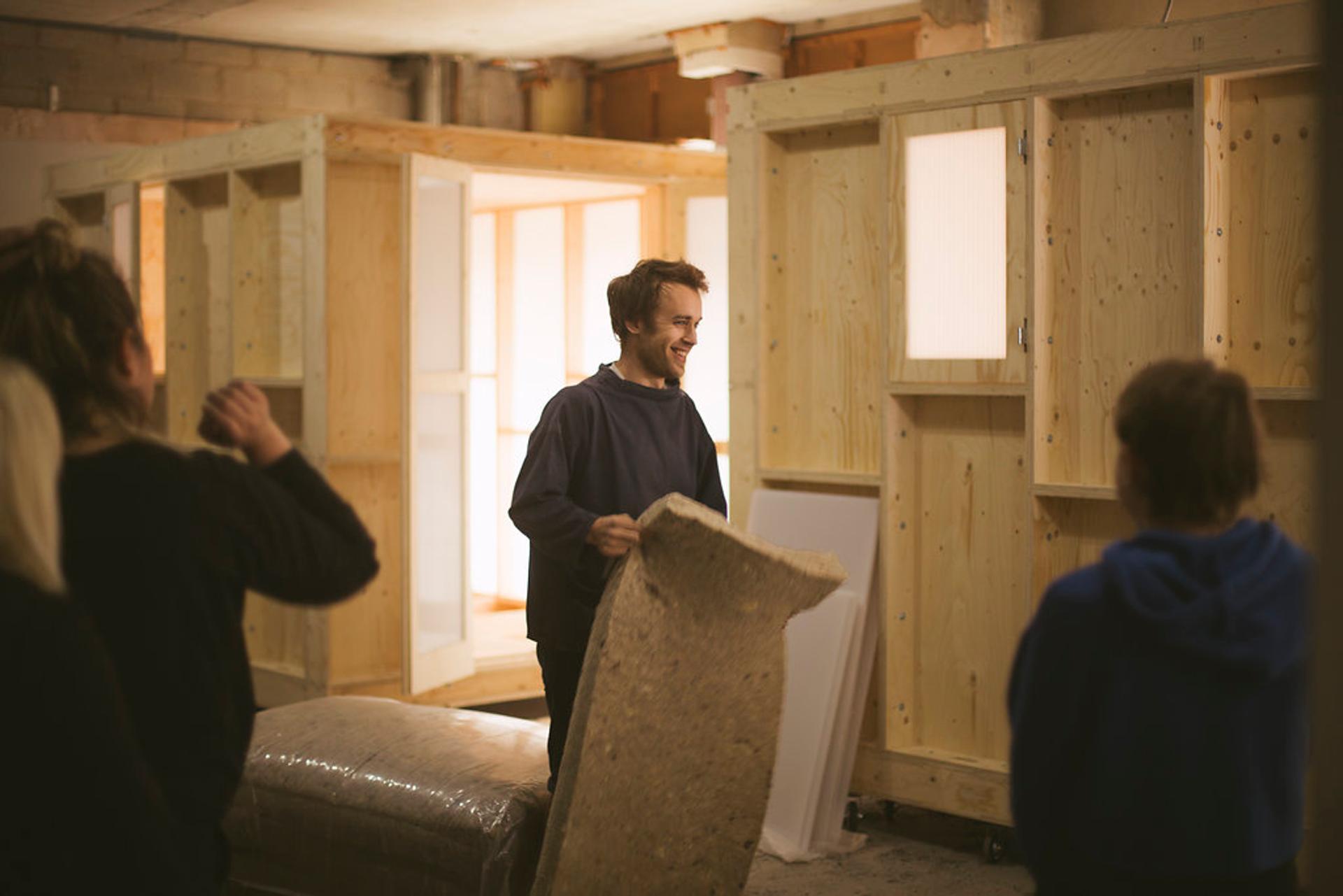 Group of students and studio members around the timber work pod
