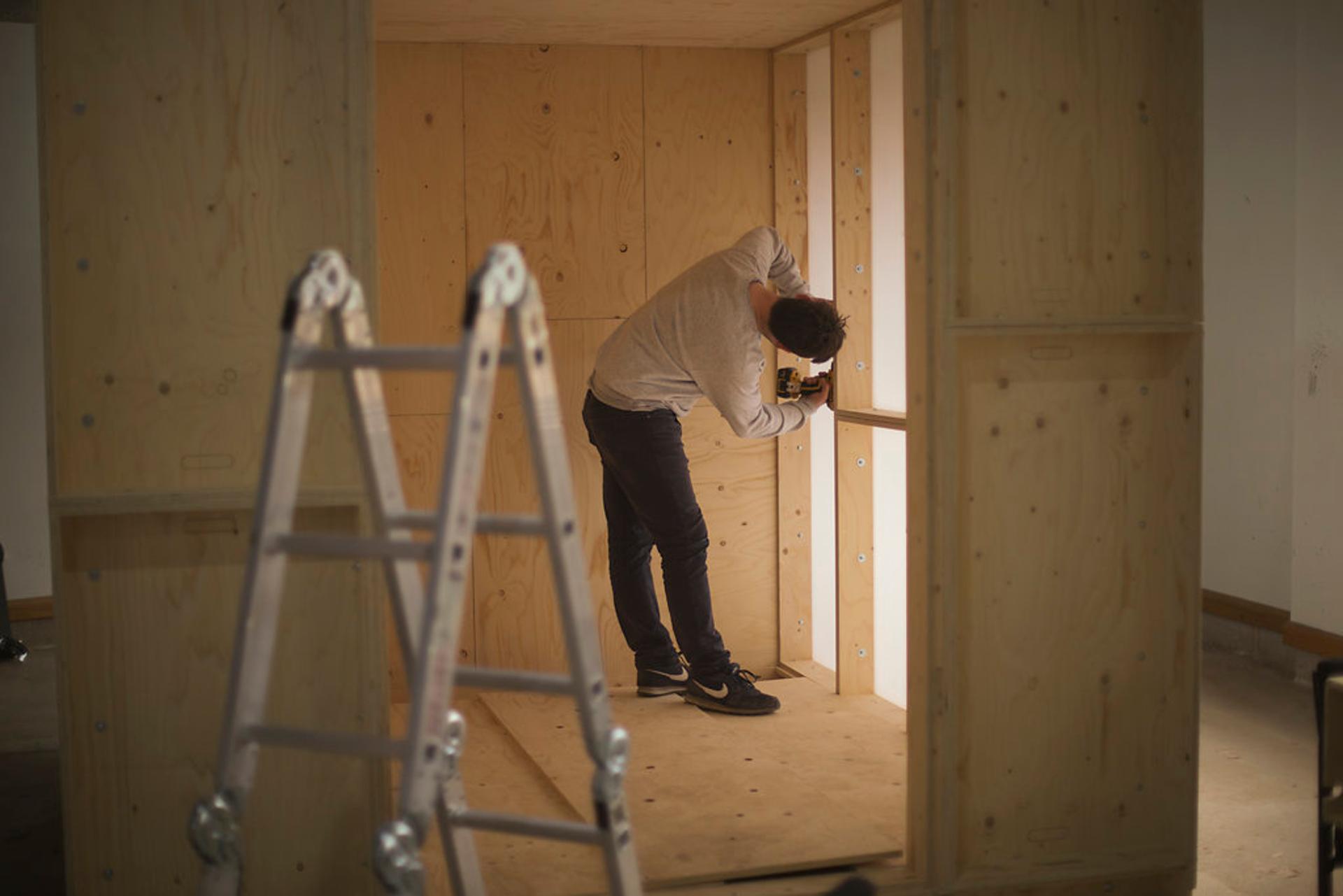 View of person fixing screws inside timber structure