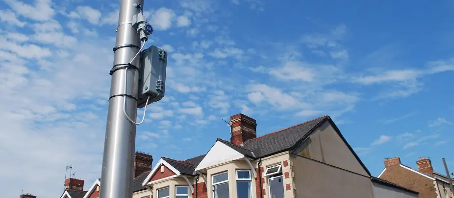 A sensor box strapped to a lamp post on a community street.