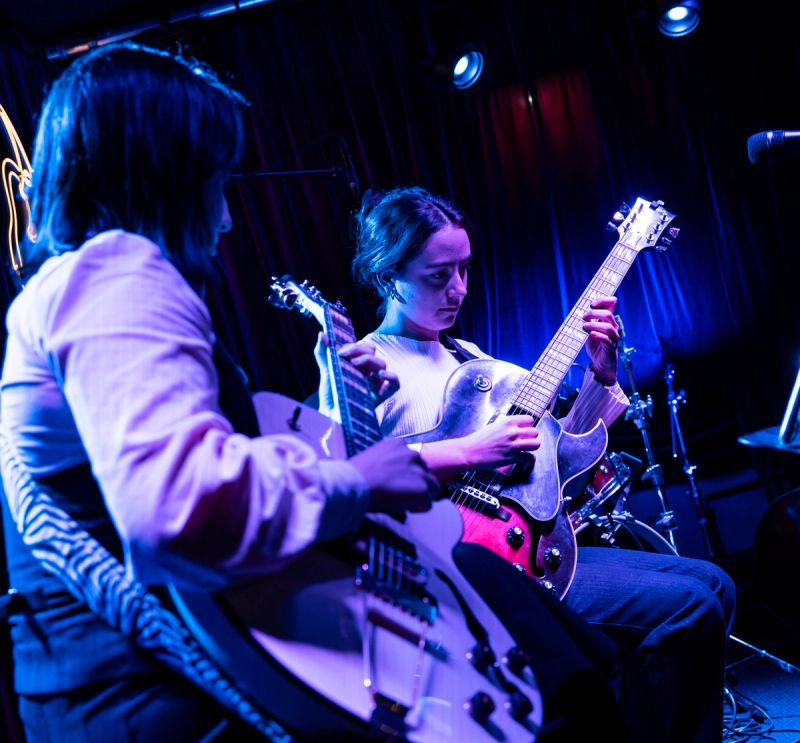 Ruby and Cicchi playing guitar, Ruby's face visible in concentration