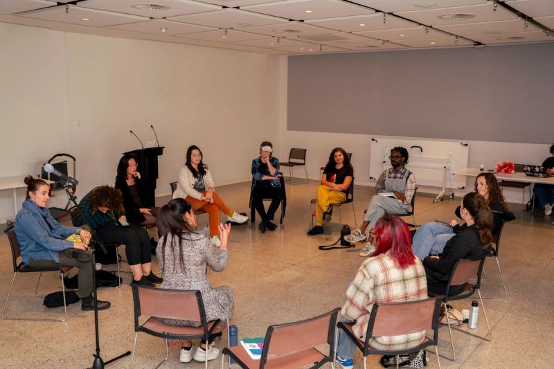 Parvyn instructing group. Everyone sitting on chairs in a circle. Whole group of 11 visible.