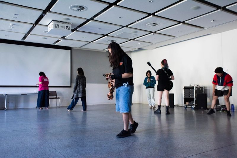 Participants holding instruments, moving around room. 