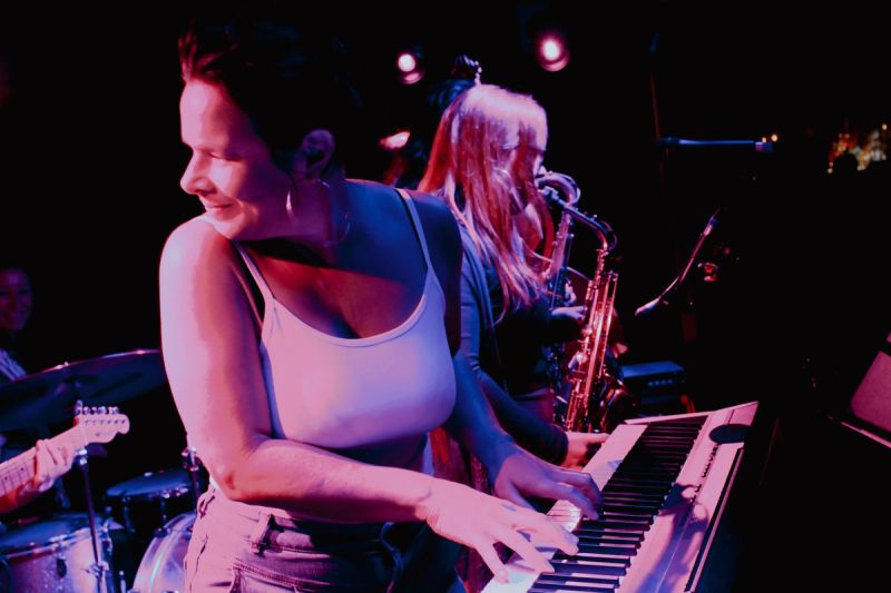 keys player looking back towards band whilst playing, two saxes visible onstage