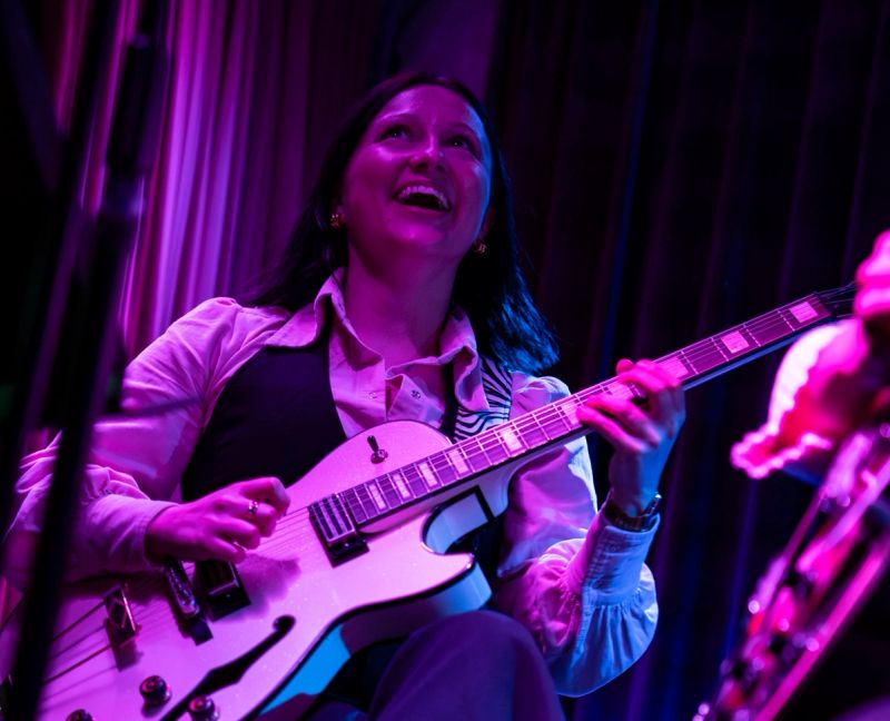 Cicchi playing guitar, looking up laughing