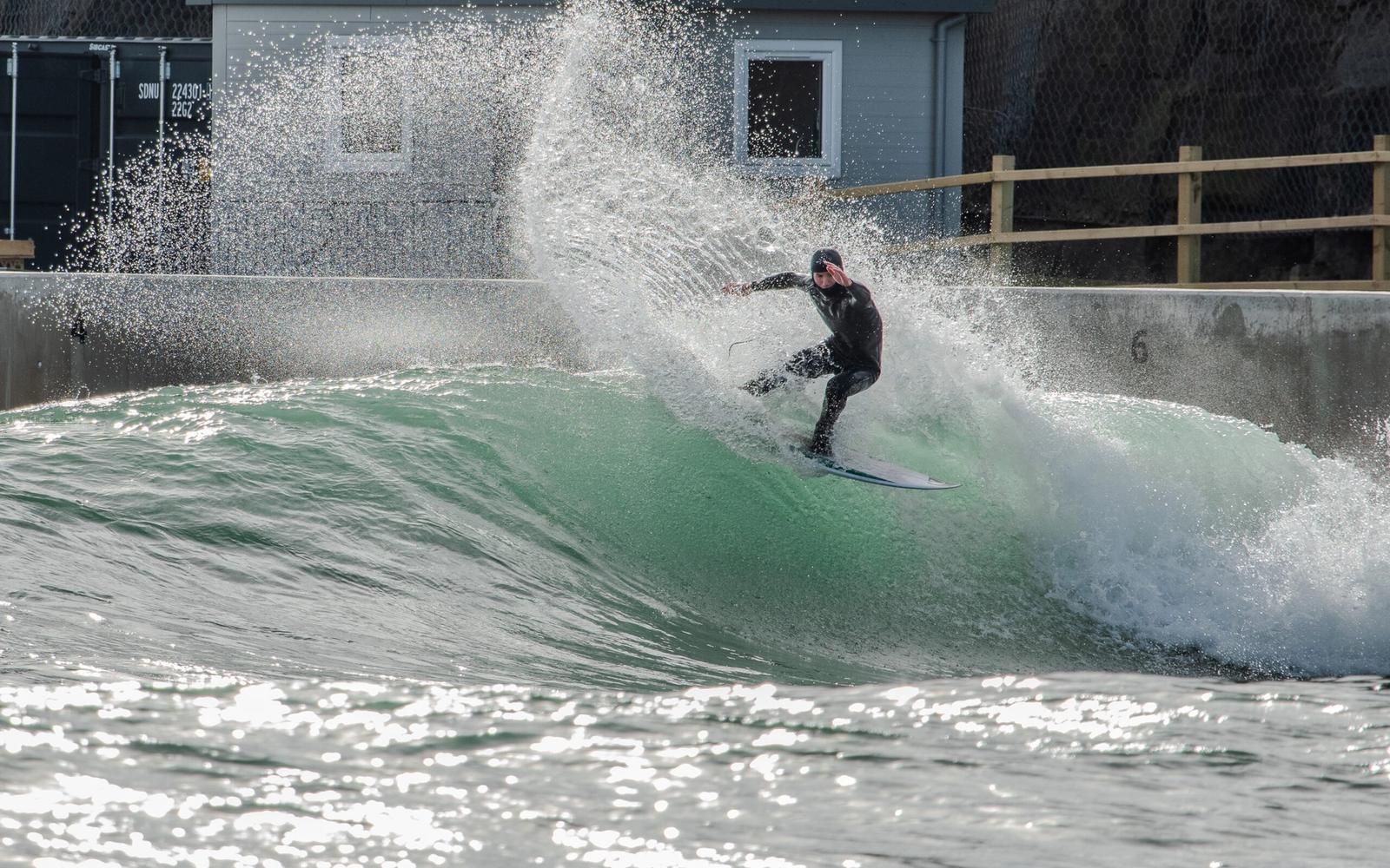 A surfer throws spray off the top of a High Performance wave at Lost Shore.