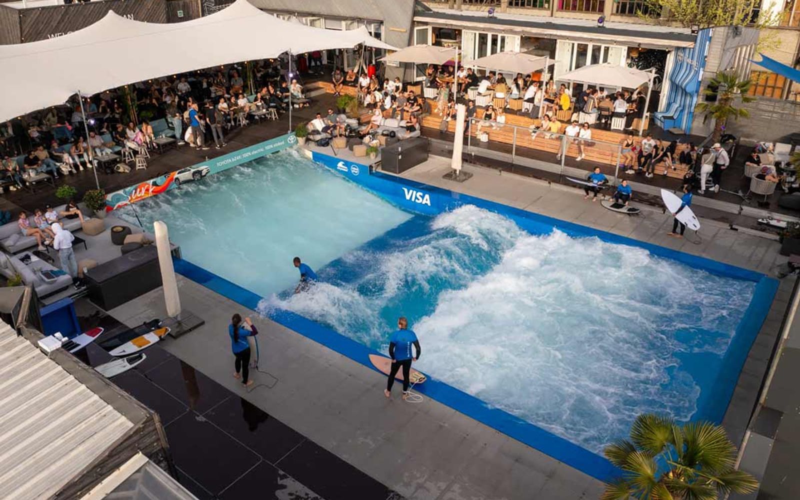 Urbansurf Zurich's pool with the terrace seating and shade sails around it.
