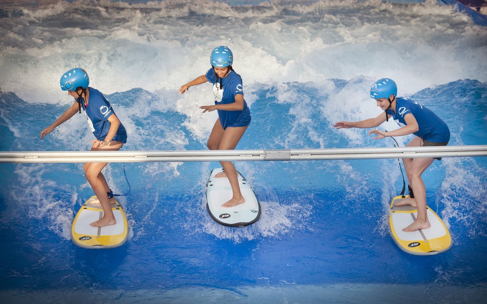 Young surfers hold the beginner bar on the wave at Citywave Vienna.