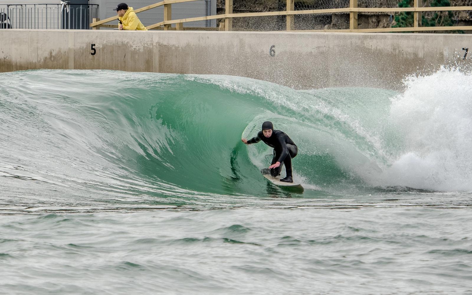 A surfer in a winter hood rides the barrel on the Barrels setting at Lost Shore.